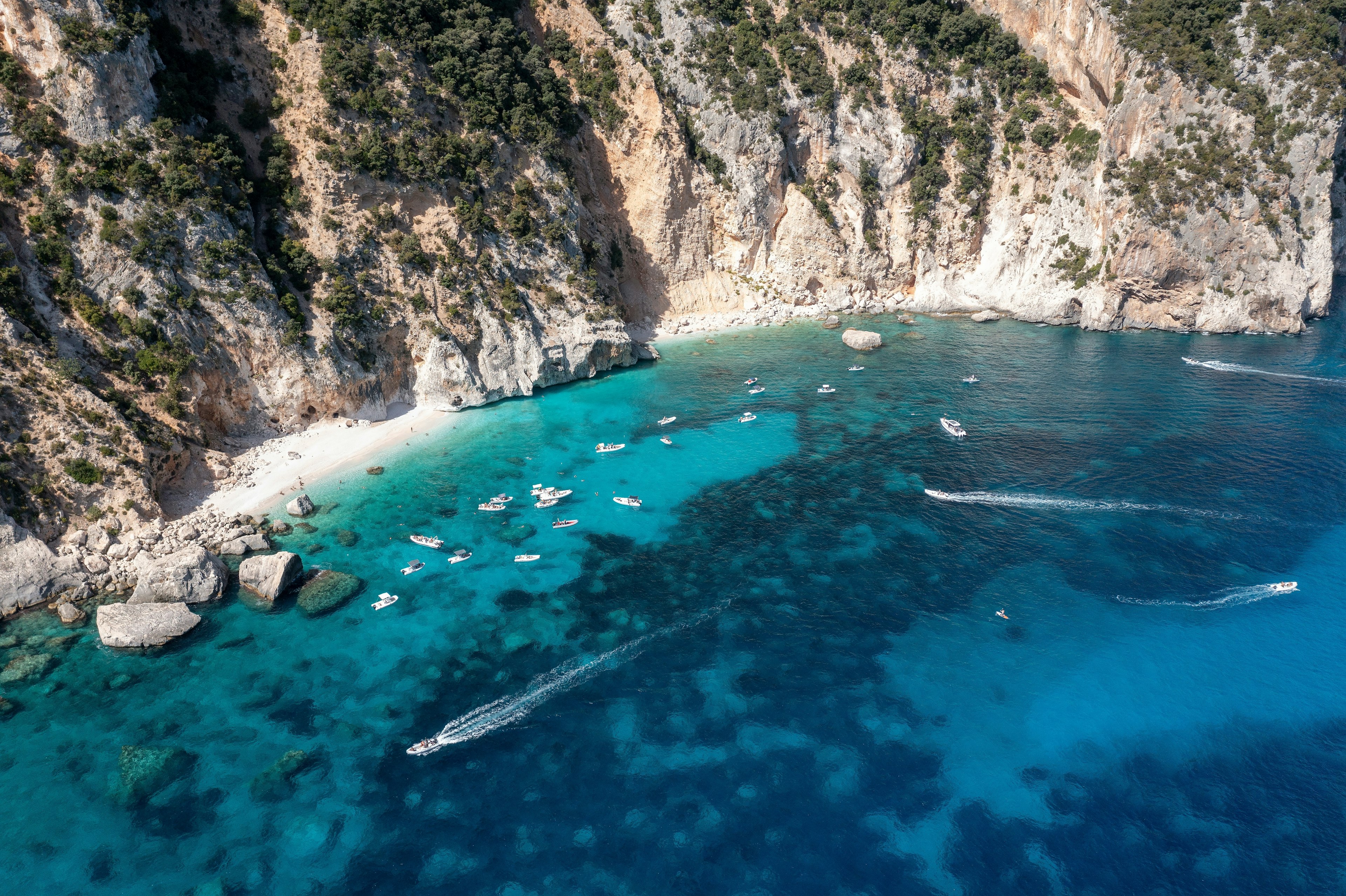 Turizmo valčių vaizdas iš oro prie tvirtos, uolos išklotos Rytų Sardinijos pakrantės Golfo di Orosei mieste netoli nuostabaus pajūrio miesto Cala Gonone.