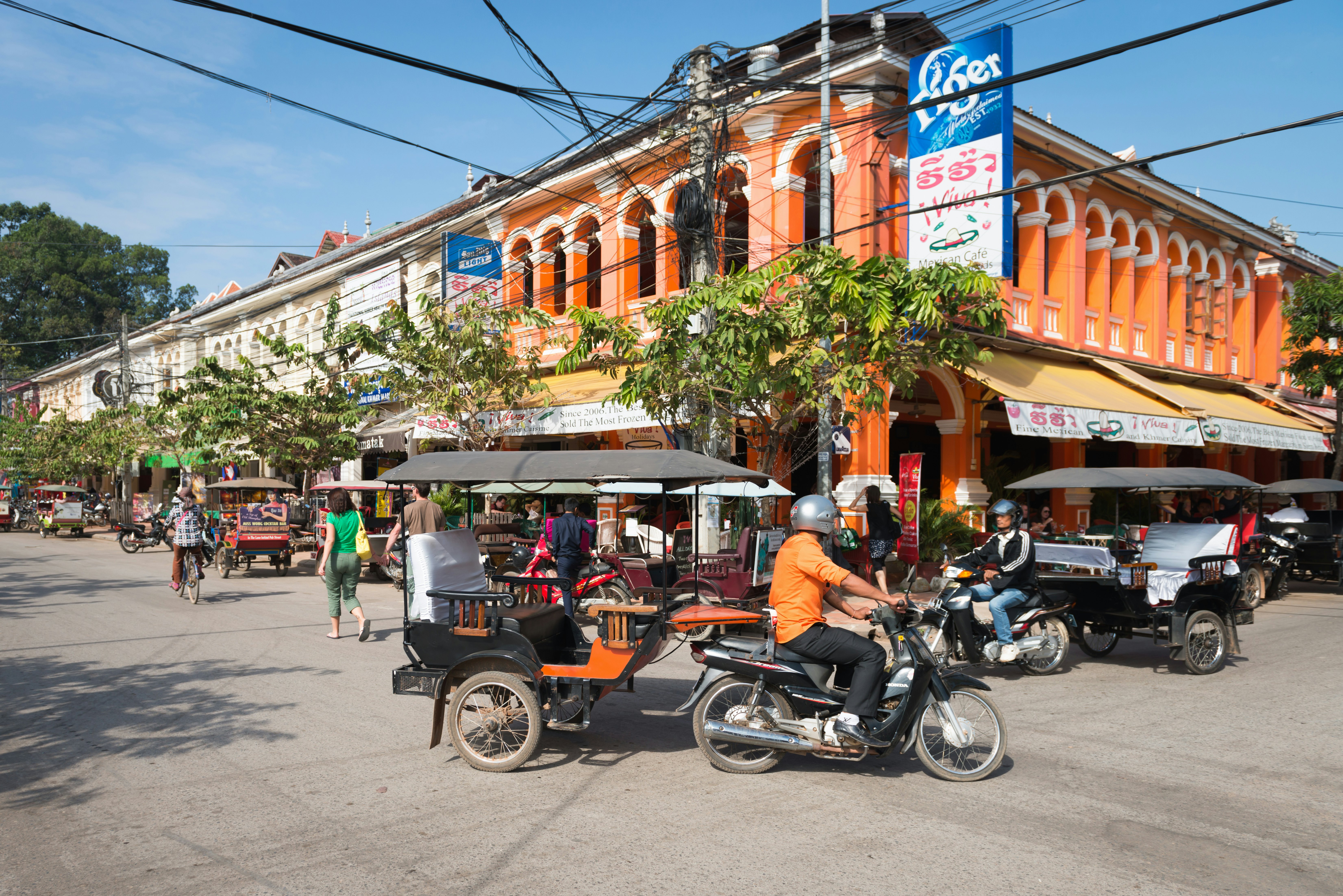 „Siem Ryp“, Kambodža-2013 m. Gruodžio 23 d .: Tuk-tuk turistinis taksi miesto centrinėje gatvėje su kolonijinėmis architektūros pastatų licencija Tipas: Media Atsisiųsti Laikas: 2023-08-01T14: 10: 00 000Z. :