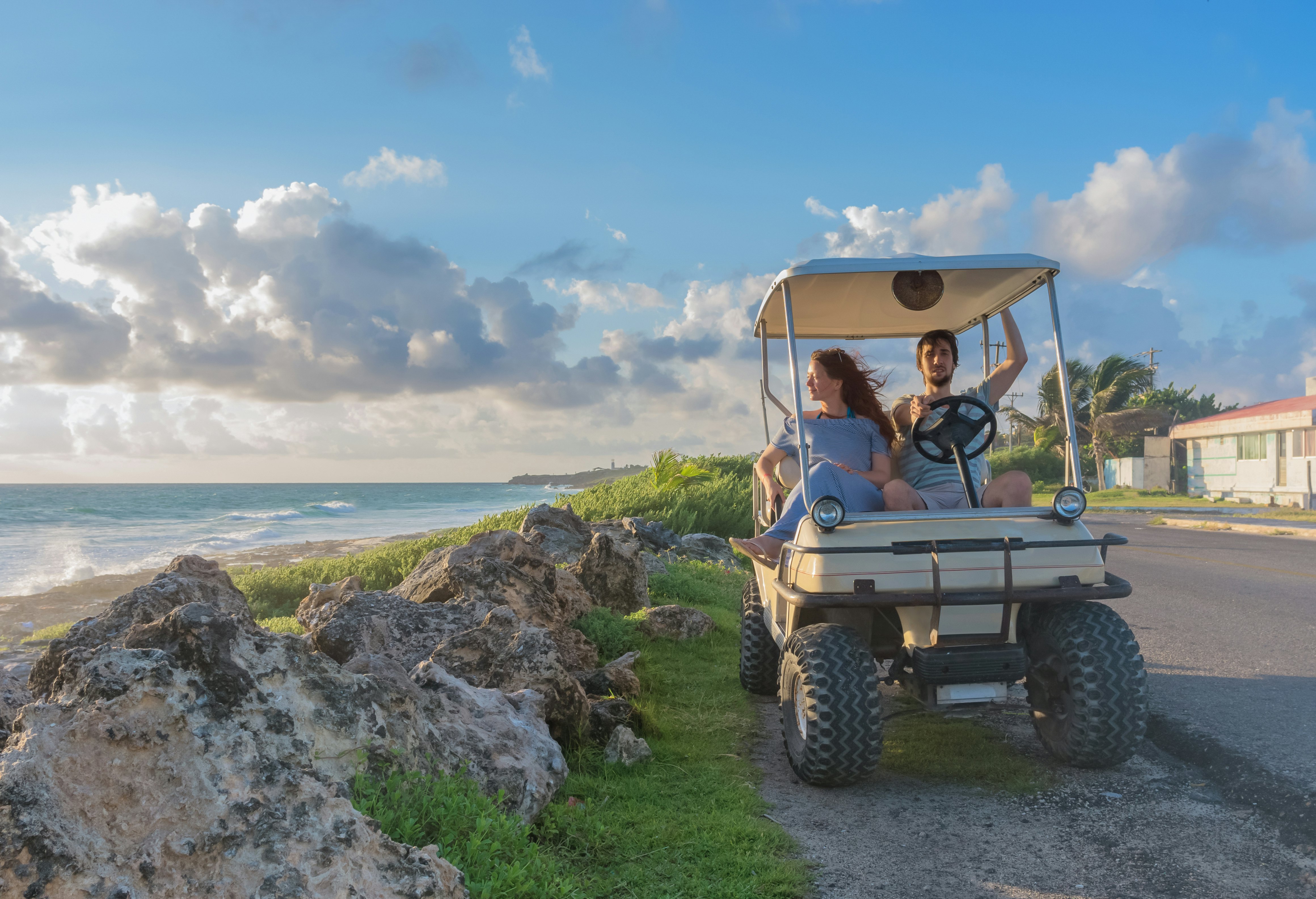 Pora, vairuojanti golfo krepšį atogrąžų paplūdimyje Isla Mujeres mieste, Meksikoje