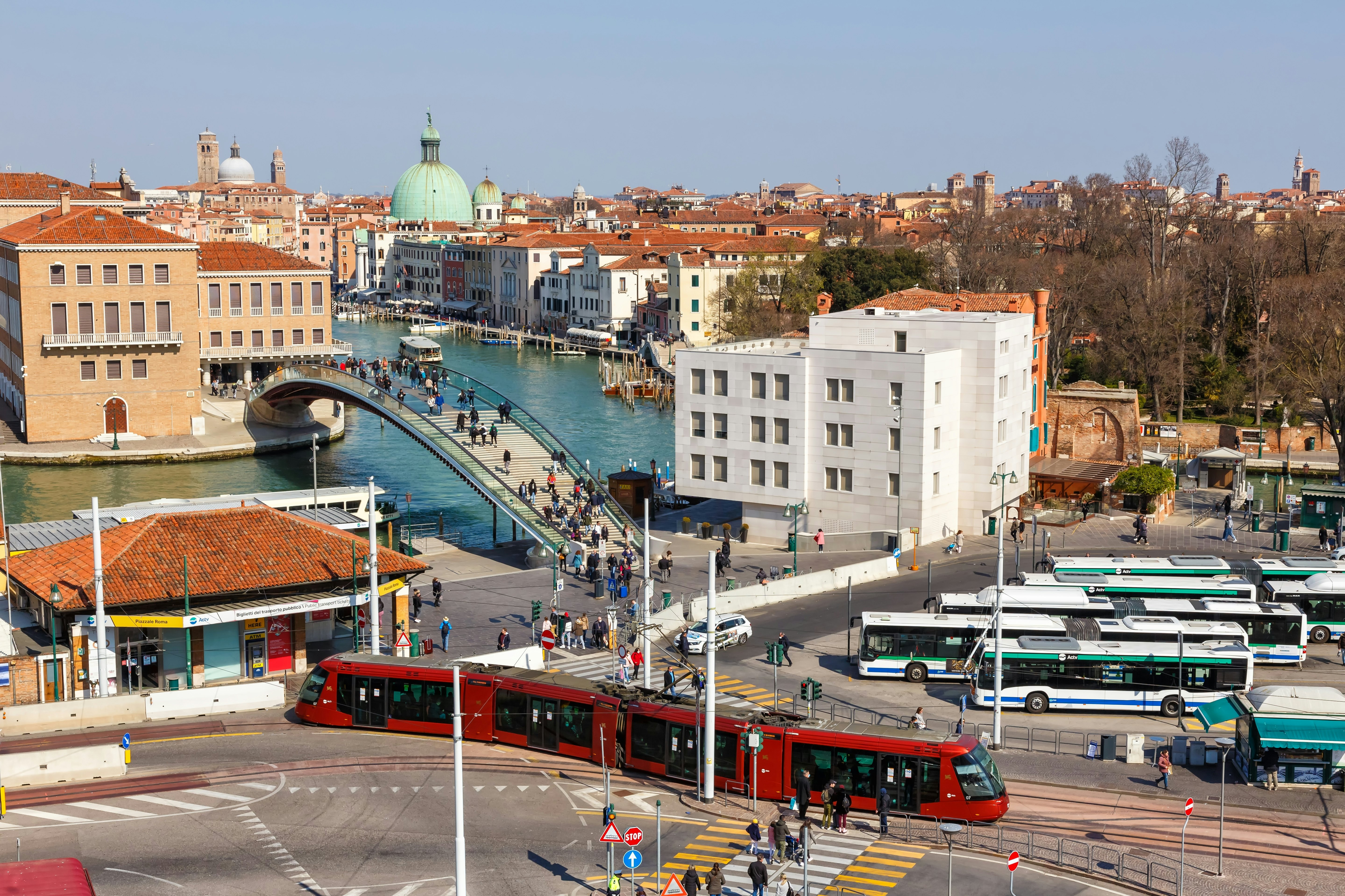 Airijos vaizdas į aikštę su tramvajumi, autobusais ir tiltu virš kanalo, o tolumoje yra stogų ir bažnyčios kupolų