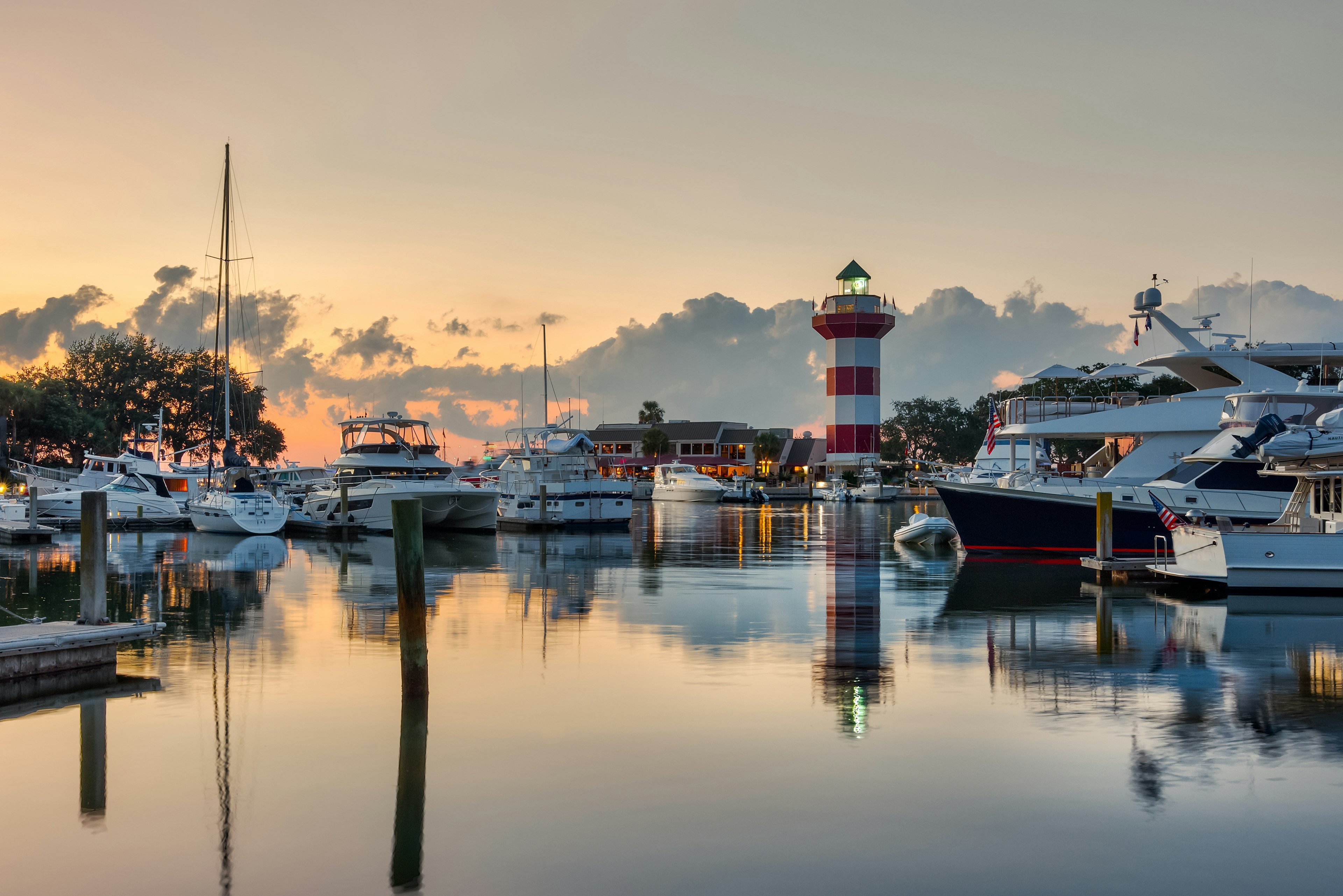 „Hilton Head Island“ ir jos ikoninis švyturys apšvietė saulėlydį su stikline, pavyzdžiui, vandeniu su valčių ir švyturio atspindžiais.
