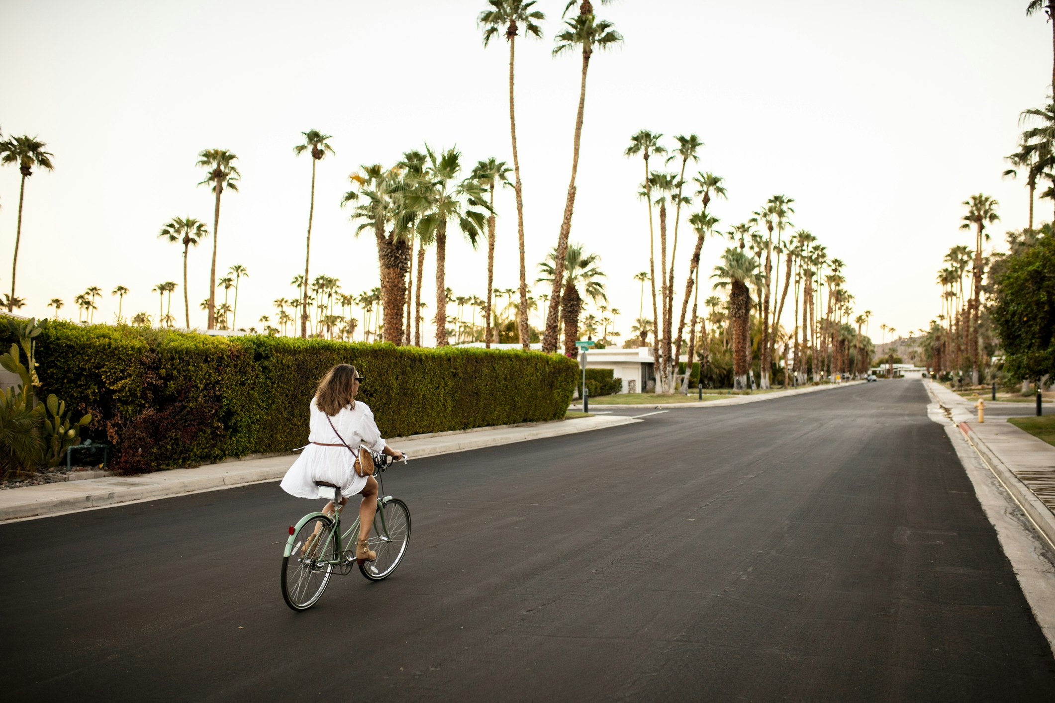 Moteris važiuoja dviračiu Palm Springs palmių gatveje, Kalifornija