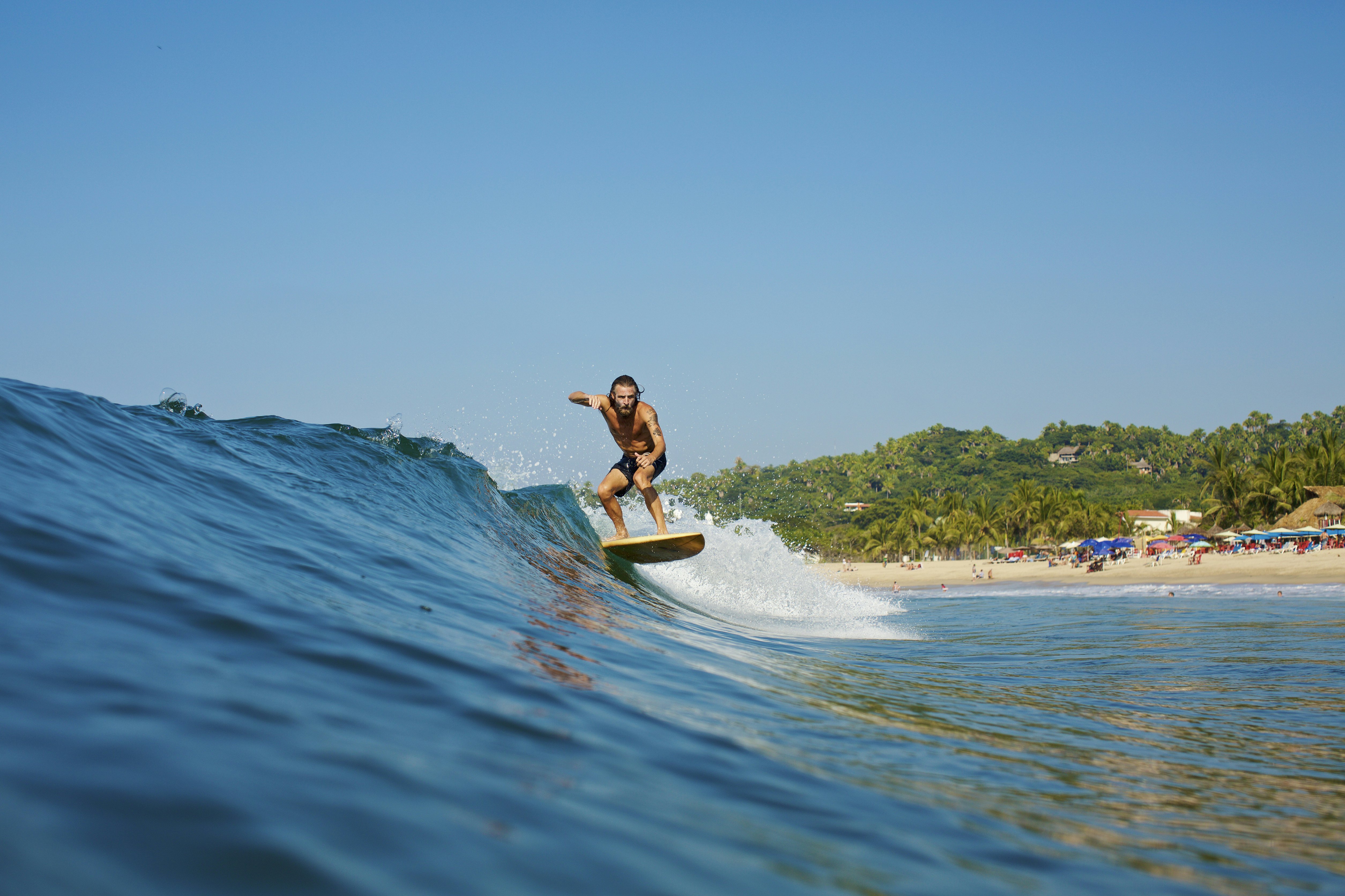 Vyras banglentininkas važiuoja banga prie kranto, Sayulita, Nayarit, Meksika