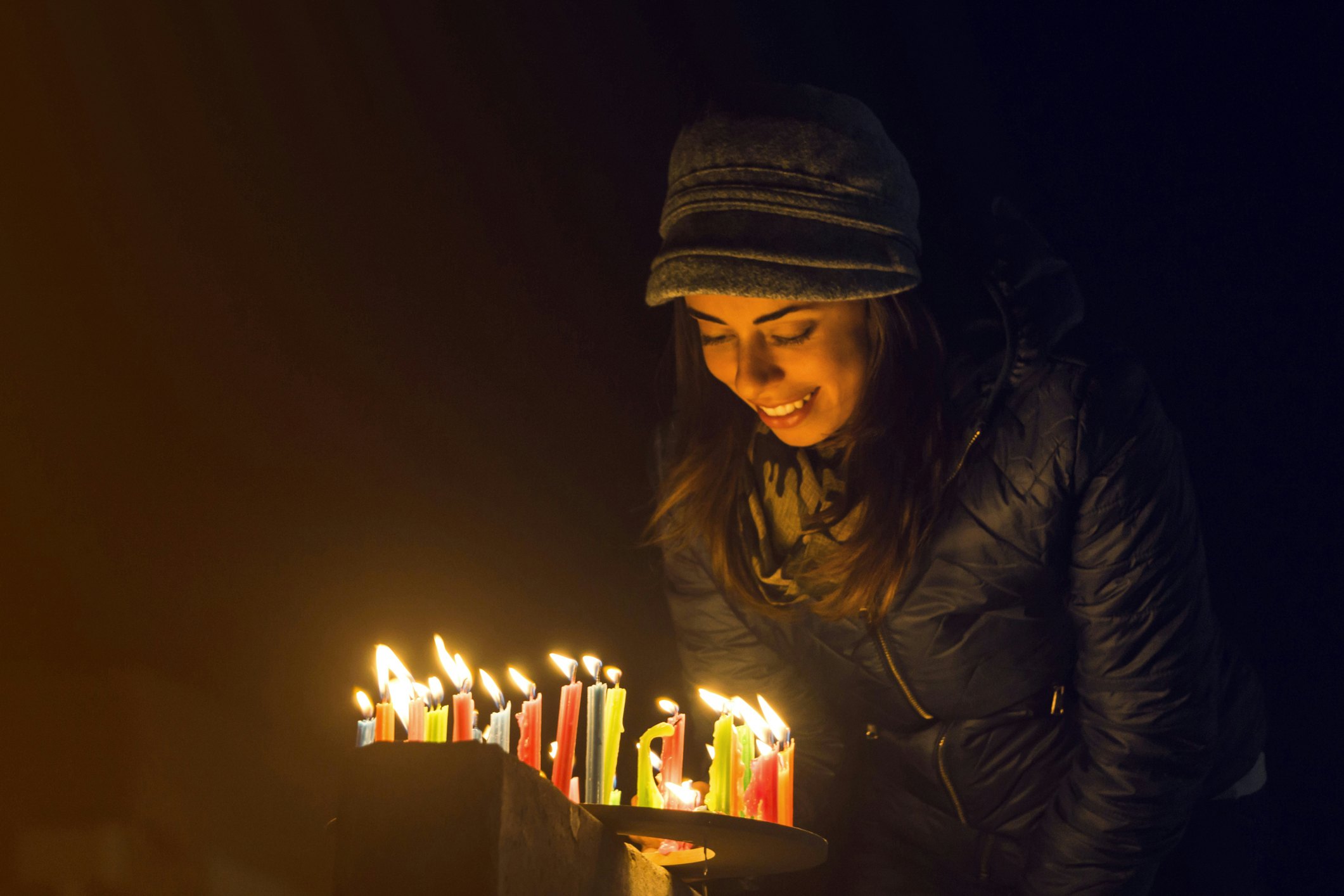 Laiminga Kolumbijos moteris, uždeganti žvakes lauke per „Noche de Velitas“ šventę, kuri vyksta gruodžio 7 d., Ir žymi Kalėdų laiko pradžią