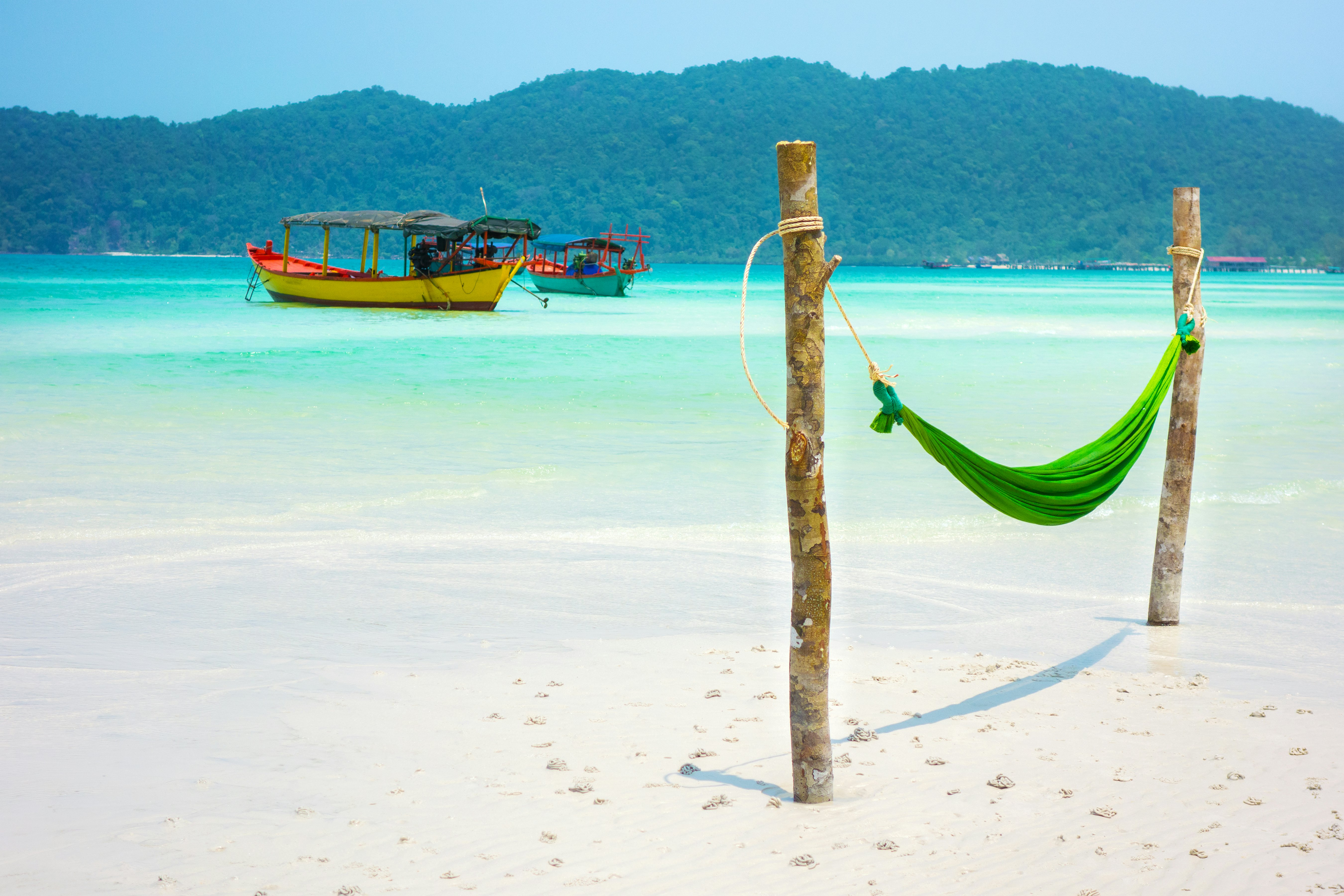 Hamakas Koh Rong Samloem paplūdimyje su dviem valtimis, pritvirtintais prie kranto.