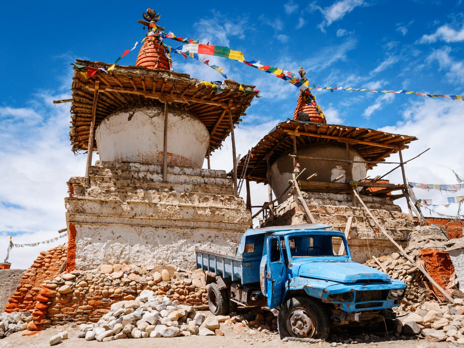 Priešais senovinį Tibeto budistų chortensą (stupos) yra sudužęs mėlynasis kinų sunkvežimis, kuris yra atkuriamas Lo Manthang mieste, netoli Tibeto sienos Nepalo.