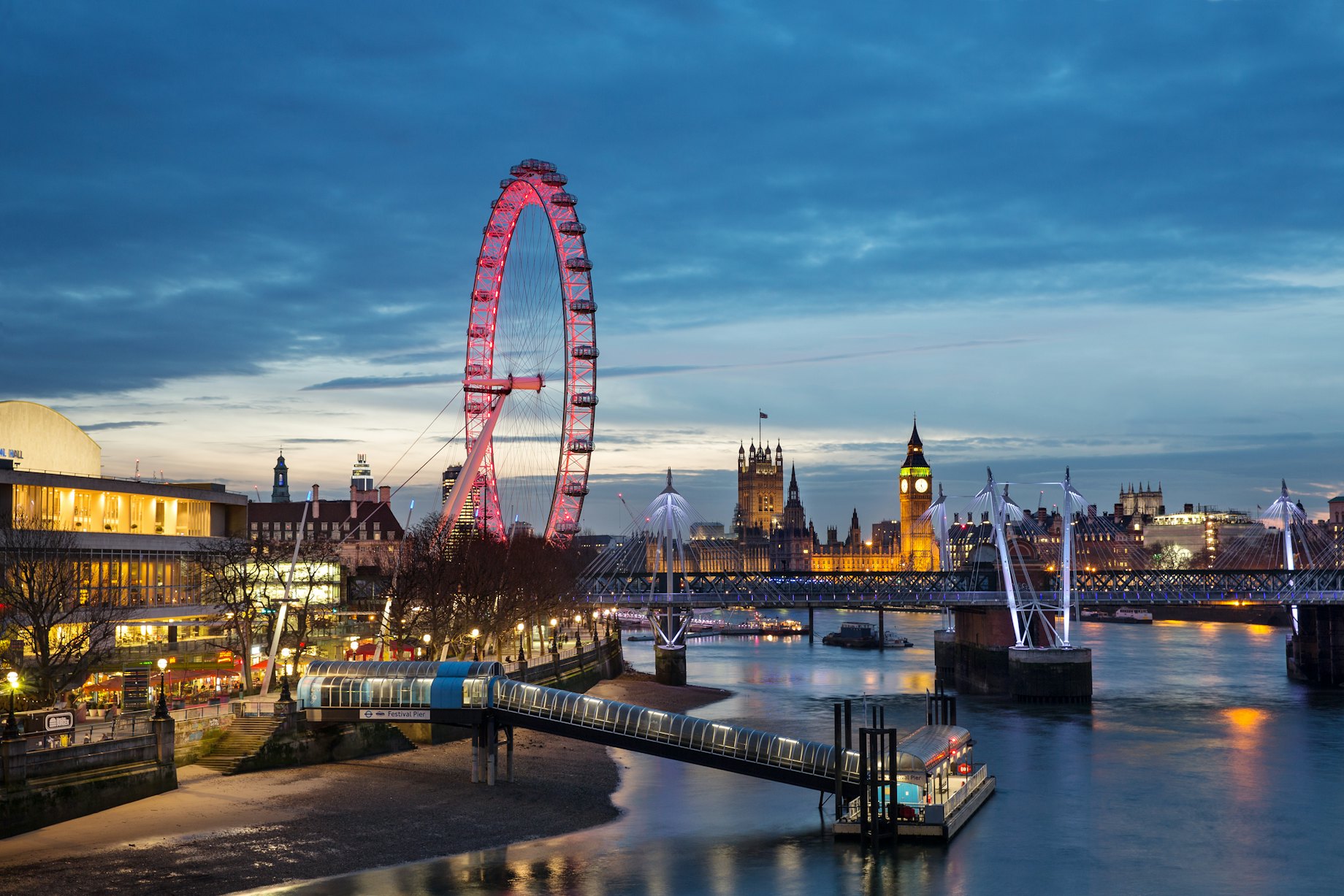A large ferris wheel beside a river at dusk