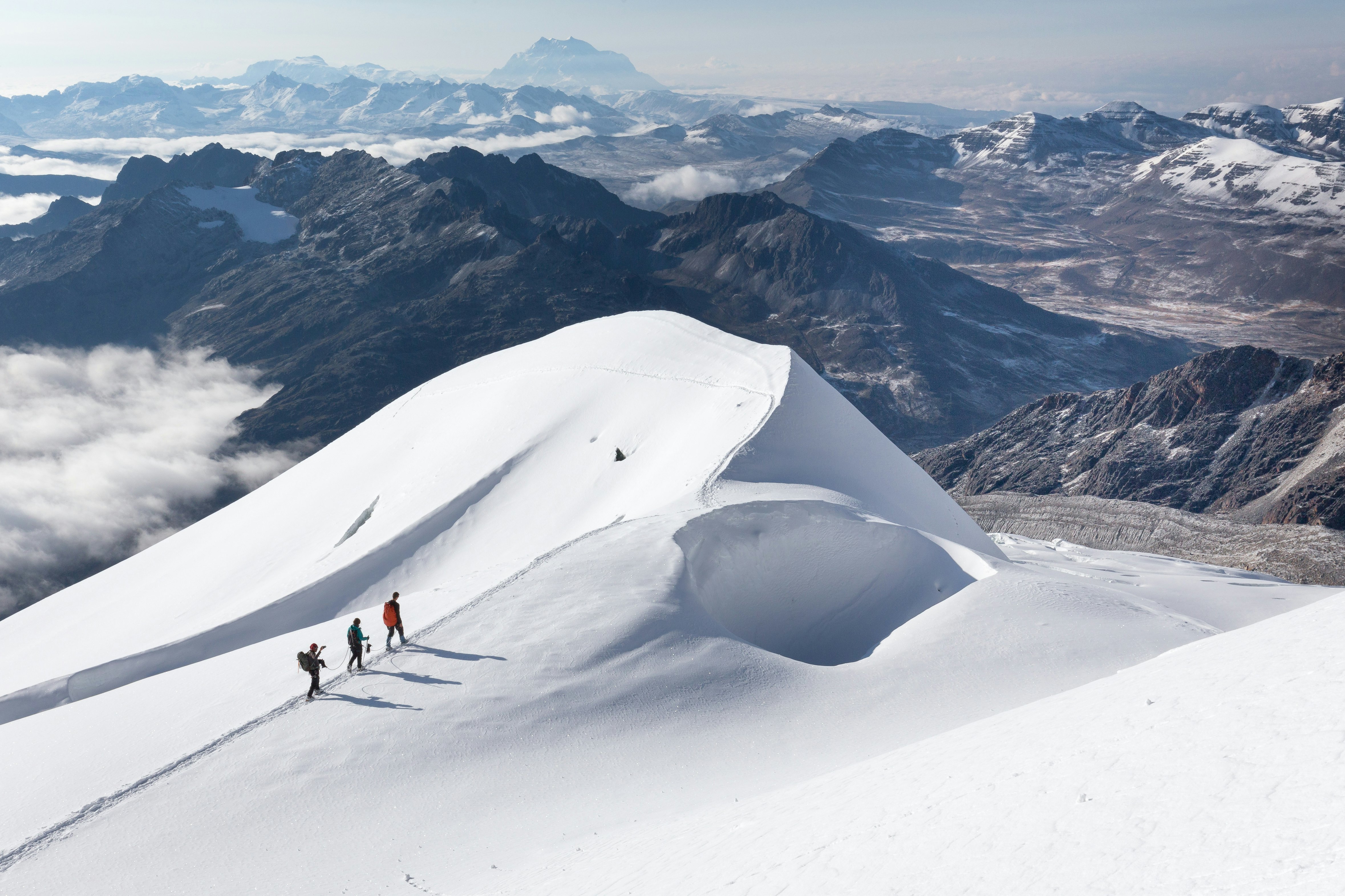 Trys alpinistai ant sniego keteros