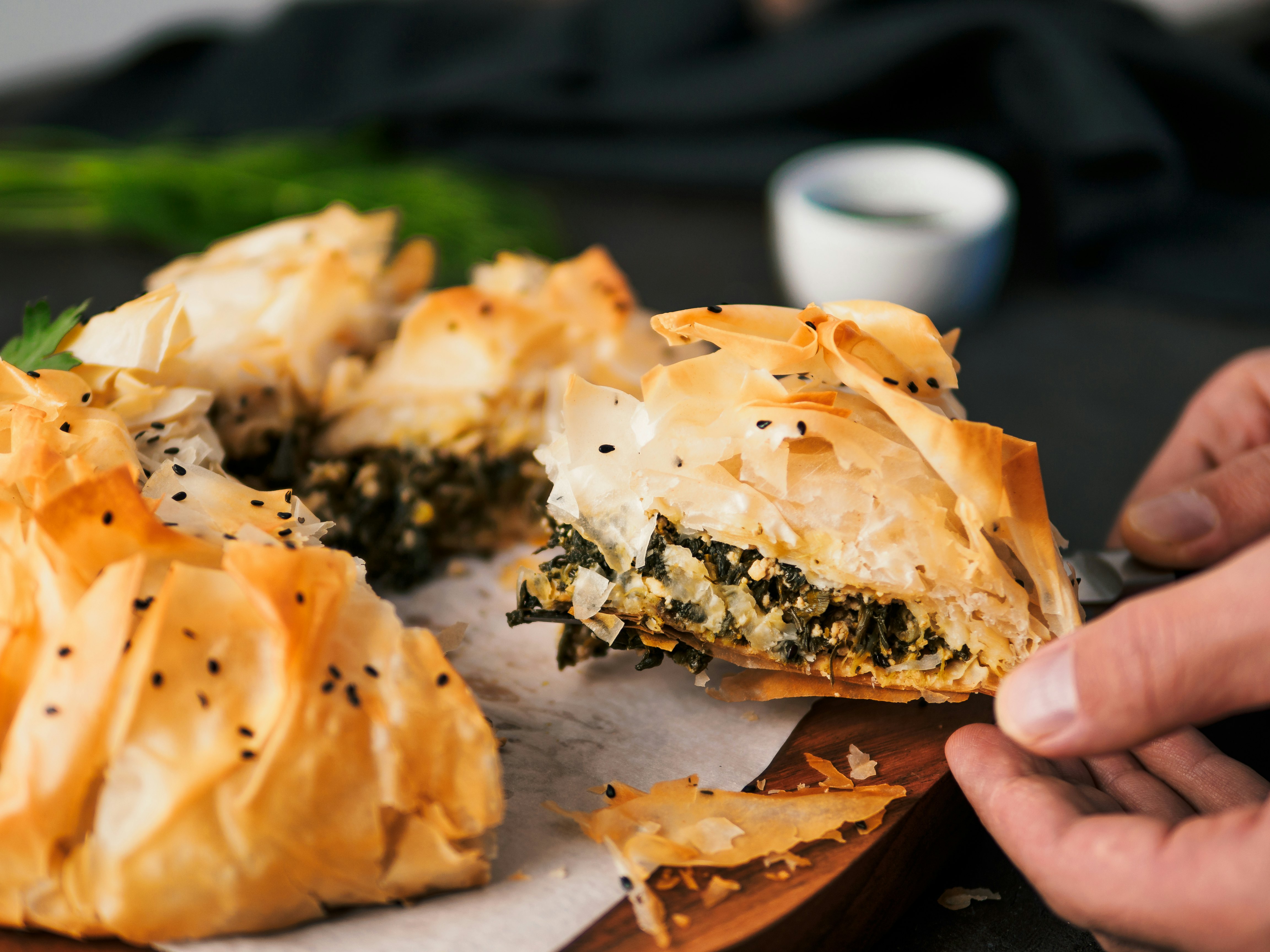 Skaniausia graikiška spanakopita pyrago gabalėlį rankoje