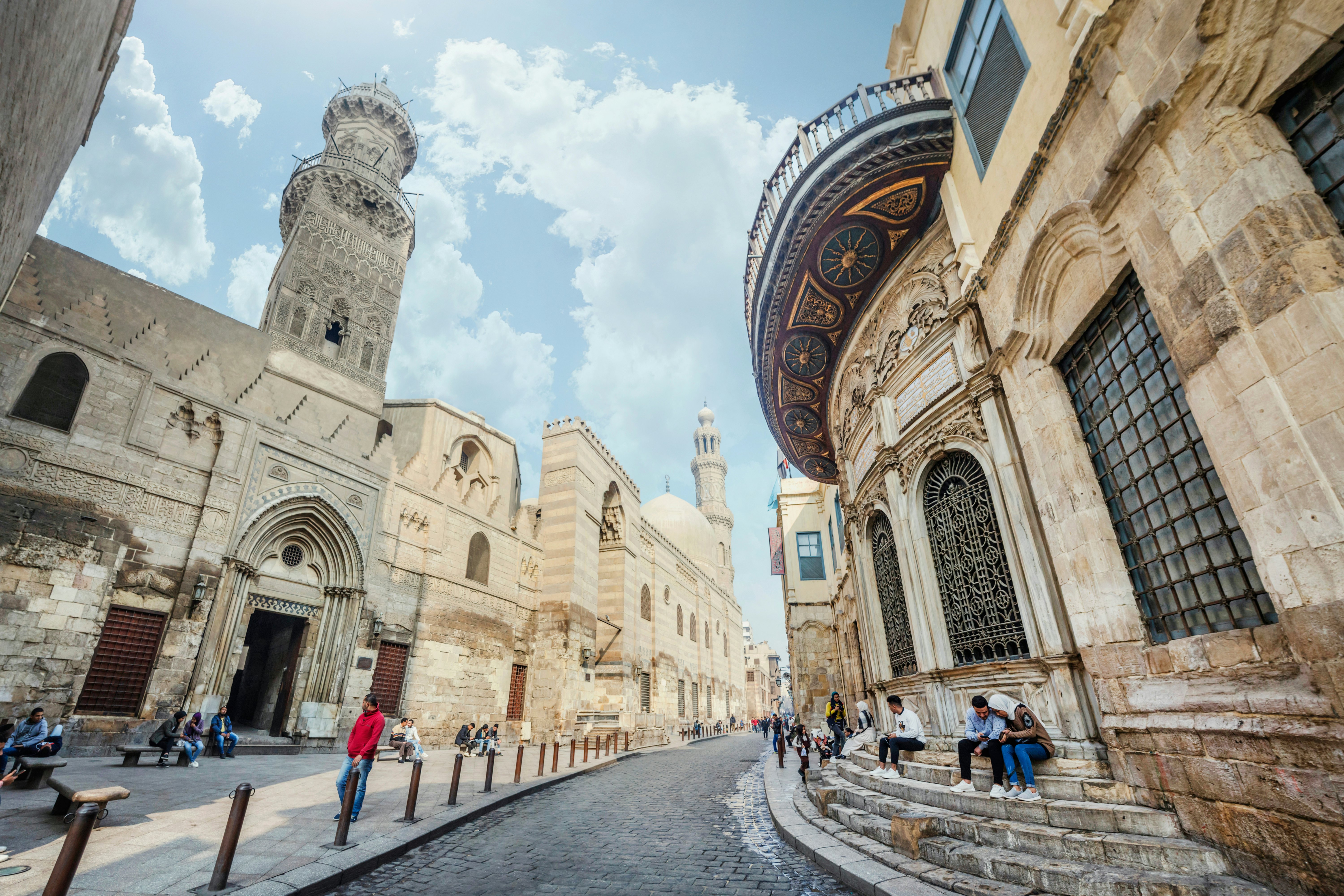 Siaura gatvė, išklota senoviniais pastatais, ir aukščiau kylanti minaretas