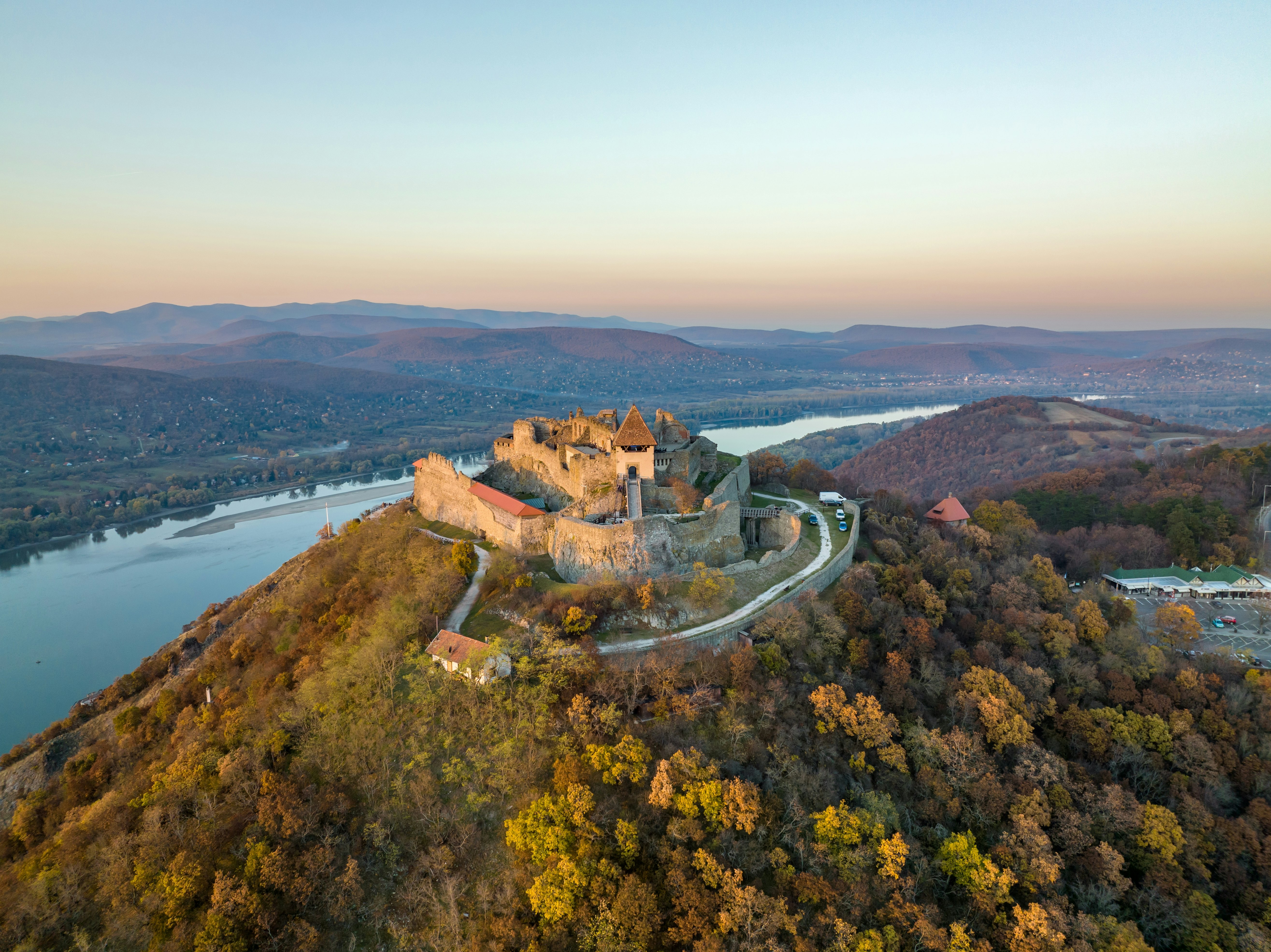 Iš oro panoraminis dronas, vaizdas į gražią Visegrado pilį ant nuotaikingo rudens saulėlydžio palei Dunojaus lenkimą (Dunakanyar) ir nuostabų „Auksinį saulėlydį“ fone.
