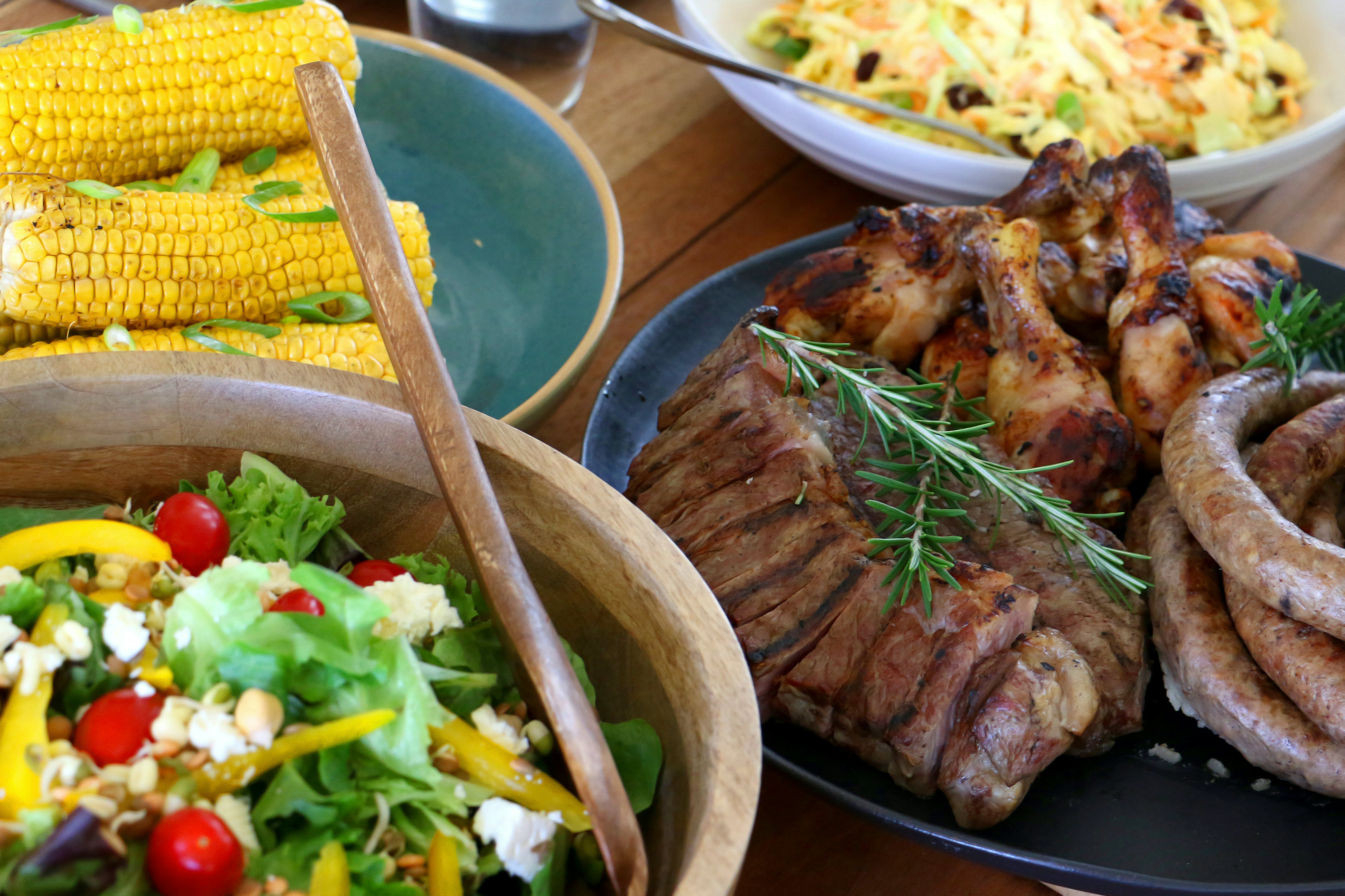 Spalvinga kepsninė „Braai“: lėkštės, kuriose yra vištienos, kepsnio, „Boerewors“ salotų ir koleslovas, išdėstytos ir paruoštos valgyti ant stalo