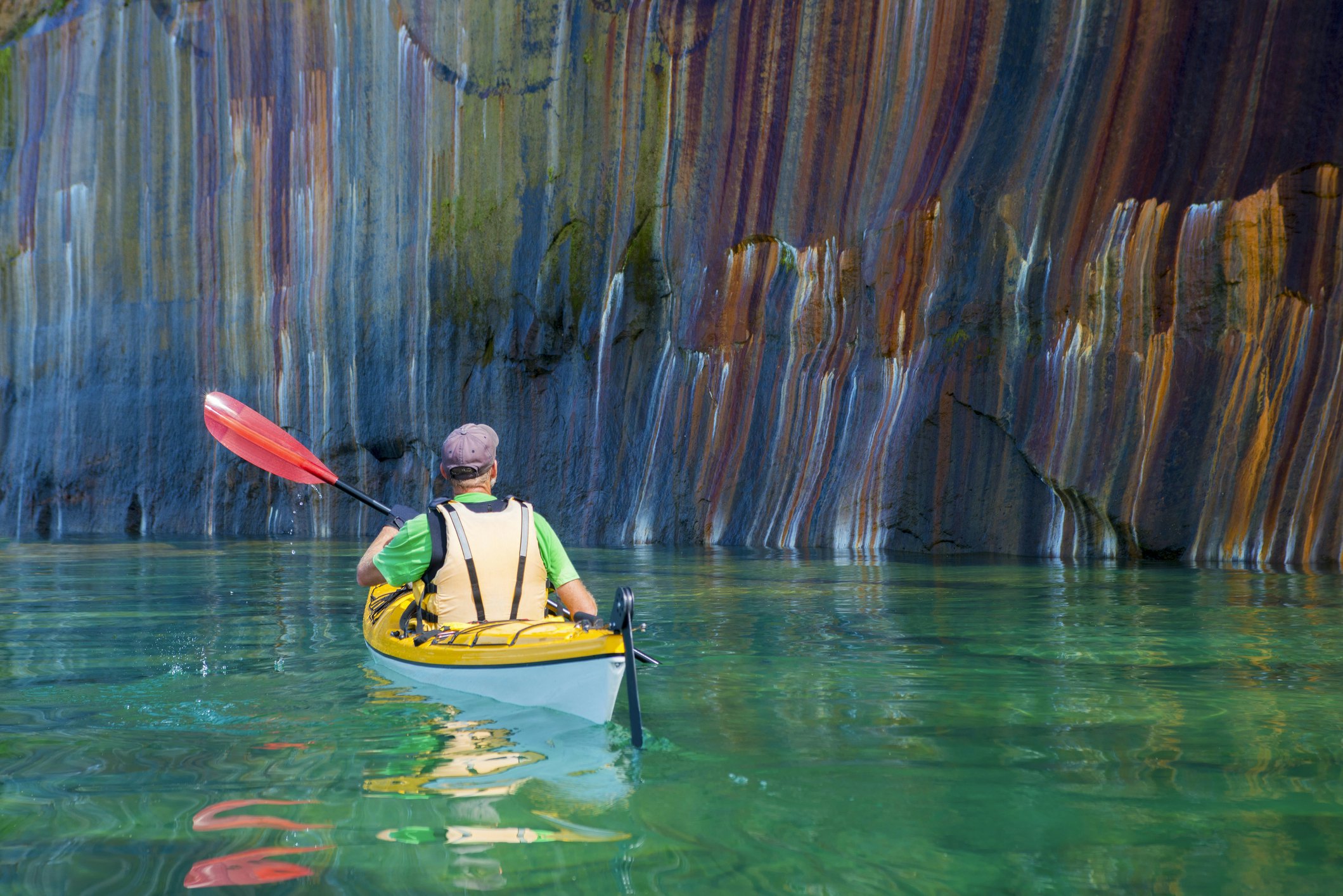 Vyras plaukia baidare pro margas Pictured Rocks uolas