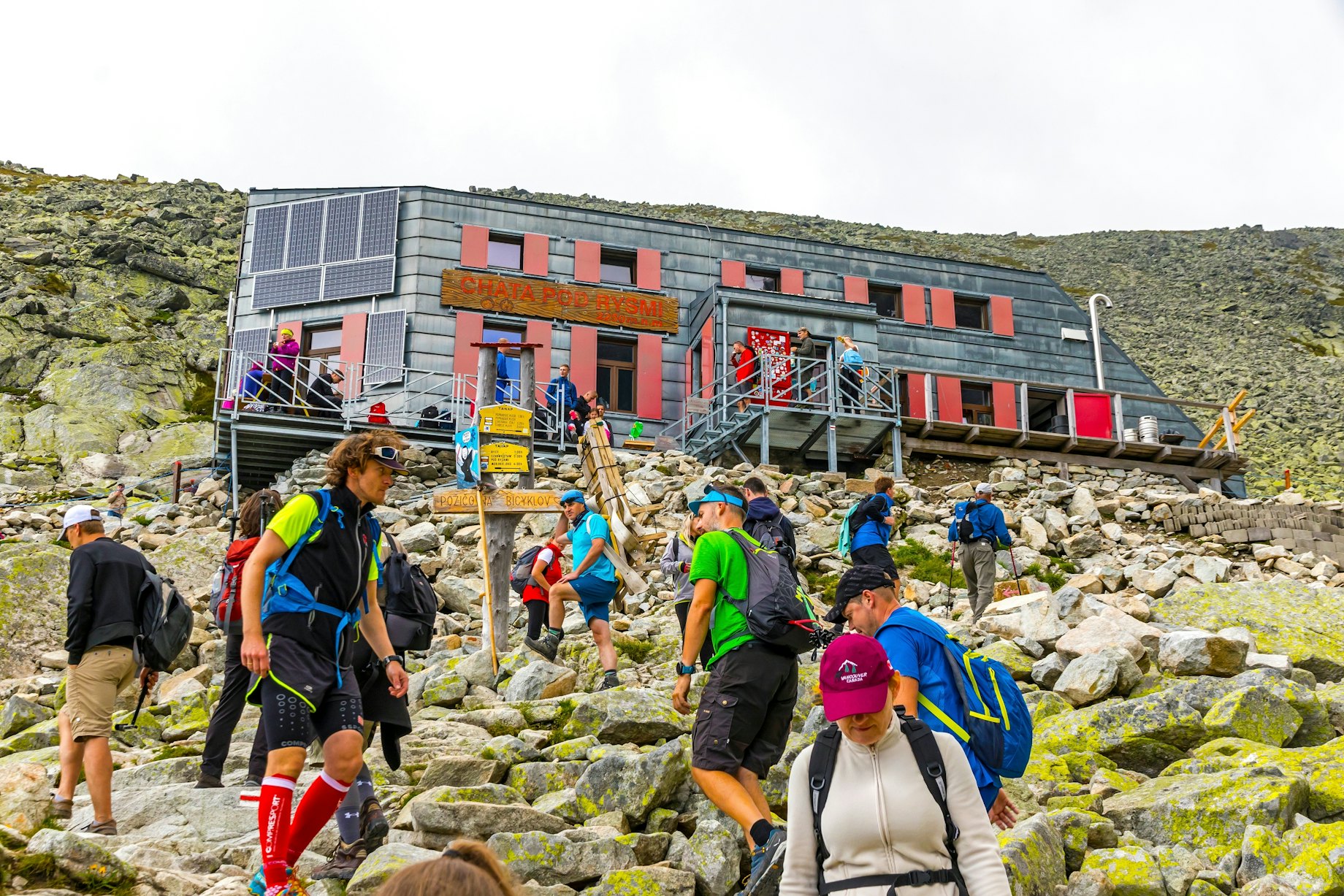 Žmonės kopia šlaitu prie Chata pod Rysmi – aukščiausiai esančios Tatrų trobelės (2250m), Slovakijoje