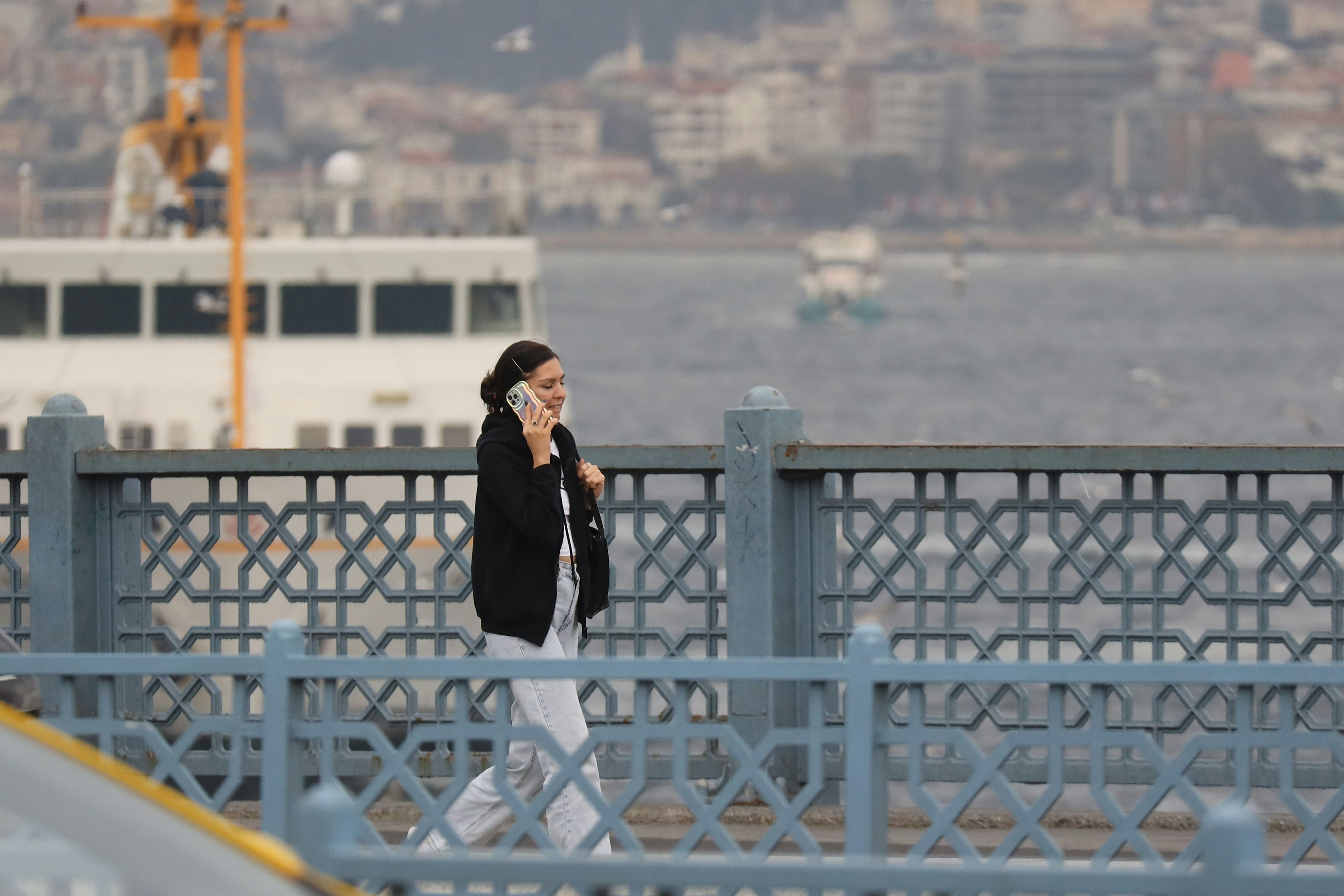 Moteris kalba telefonu, eidama ant tilto su keltu fone,