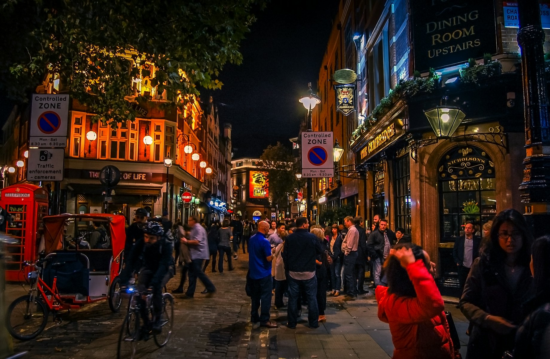 People standing on the street outside bars and pubs at night