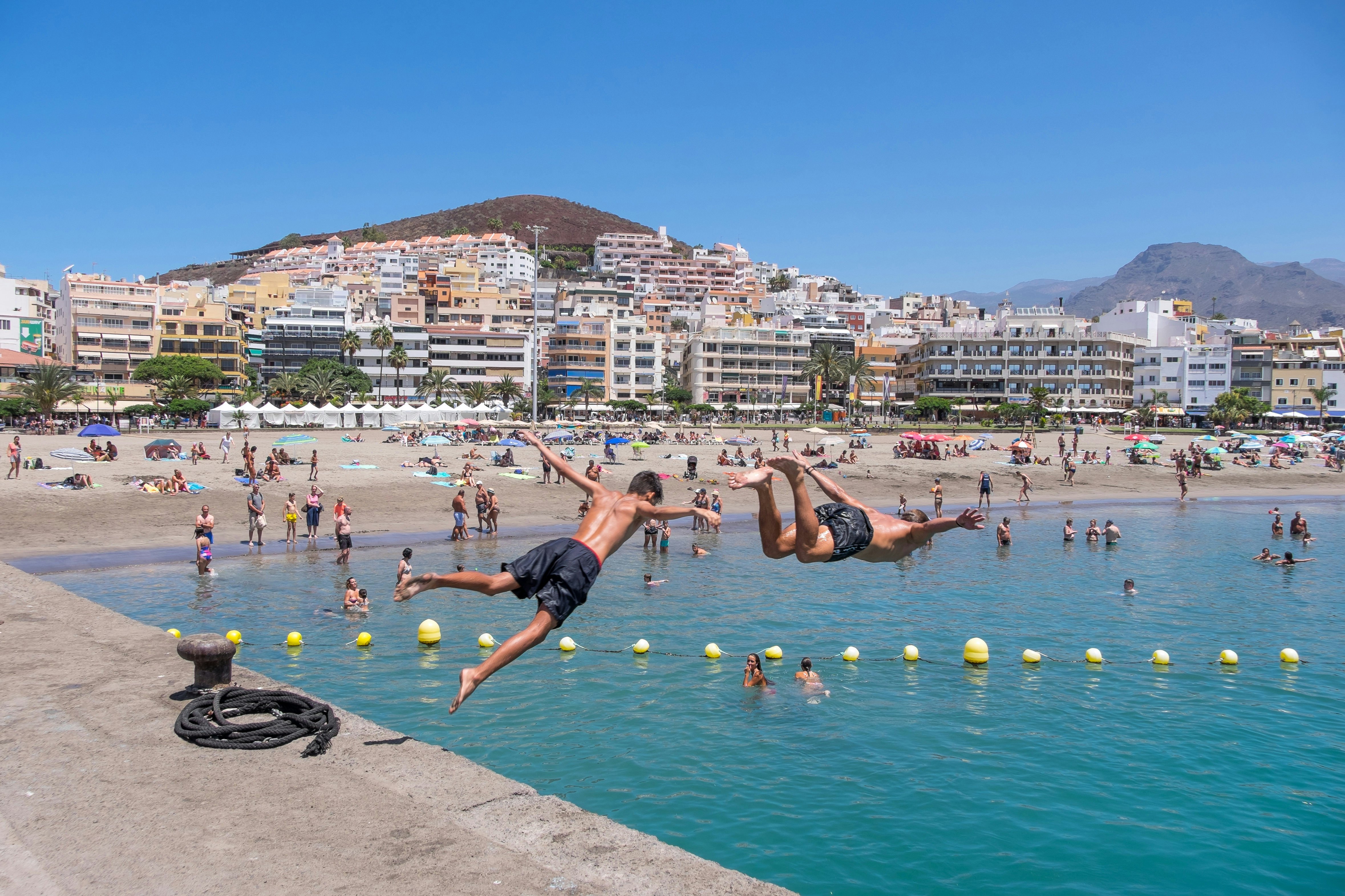 2019 m. Liepos 25 d.: Jauni berniukai, šokinėjantys į vandenį iš Los Cristianos uosto. 1465537337 africa, atlantic, beach, blue, boat, building, buildings, canary islands, city, coast, coastline, destination, editorial, europe, fish boat, harbor, harbour, holiday, island, landscape, nature, outdoor, people, port, resort, sand, sea, ship, sky, spain, spanish, summer, sunny, tenerife, tourism, touristic, town, transport, transportation, travel, vacation, view, village, water