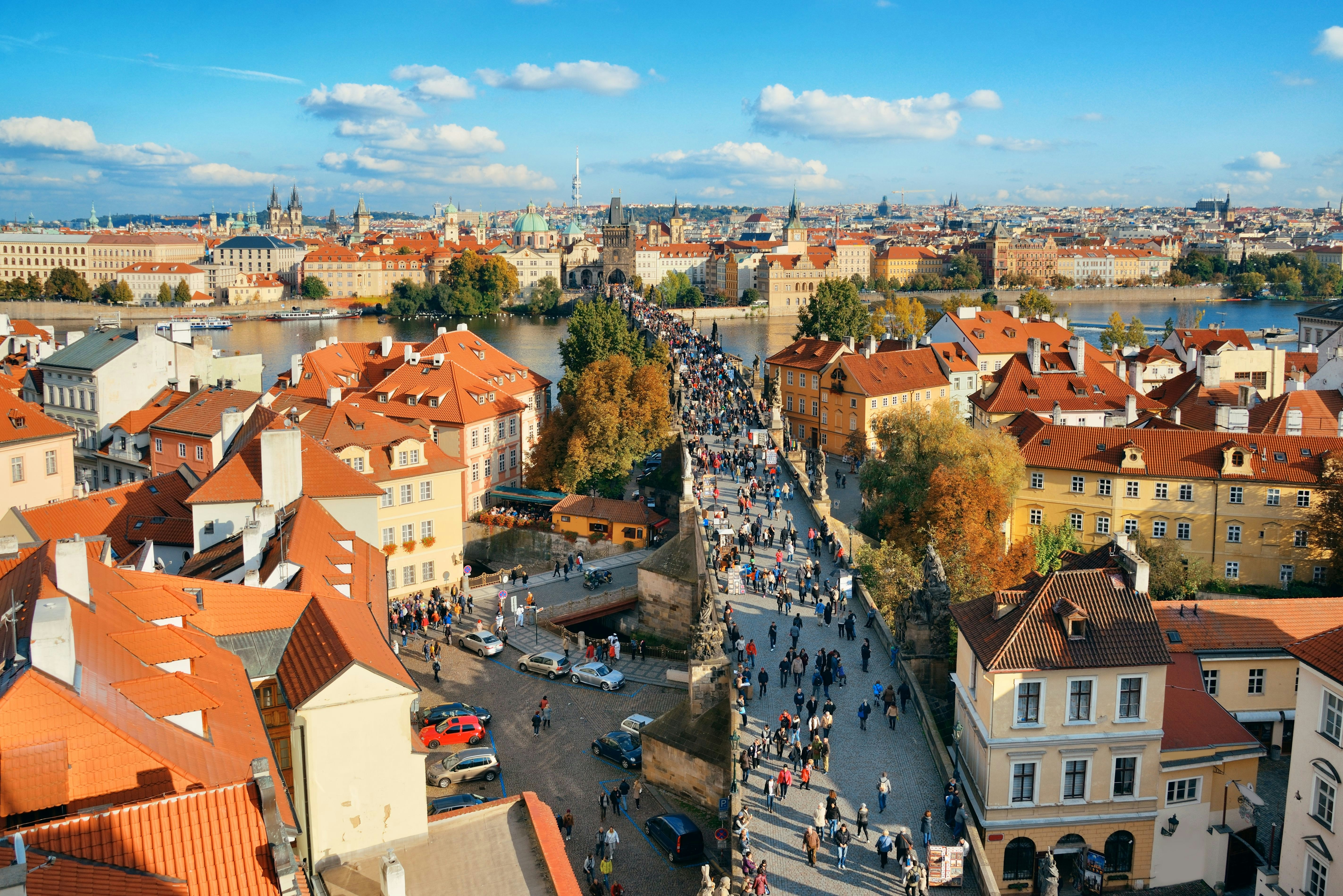 Daugybė žmonių eina pėsčiomis per tiltą šalia senamiesčio