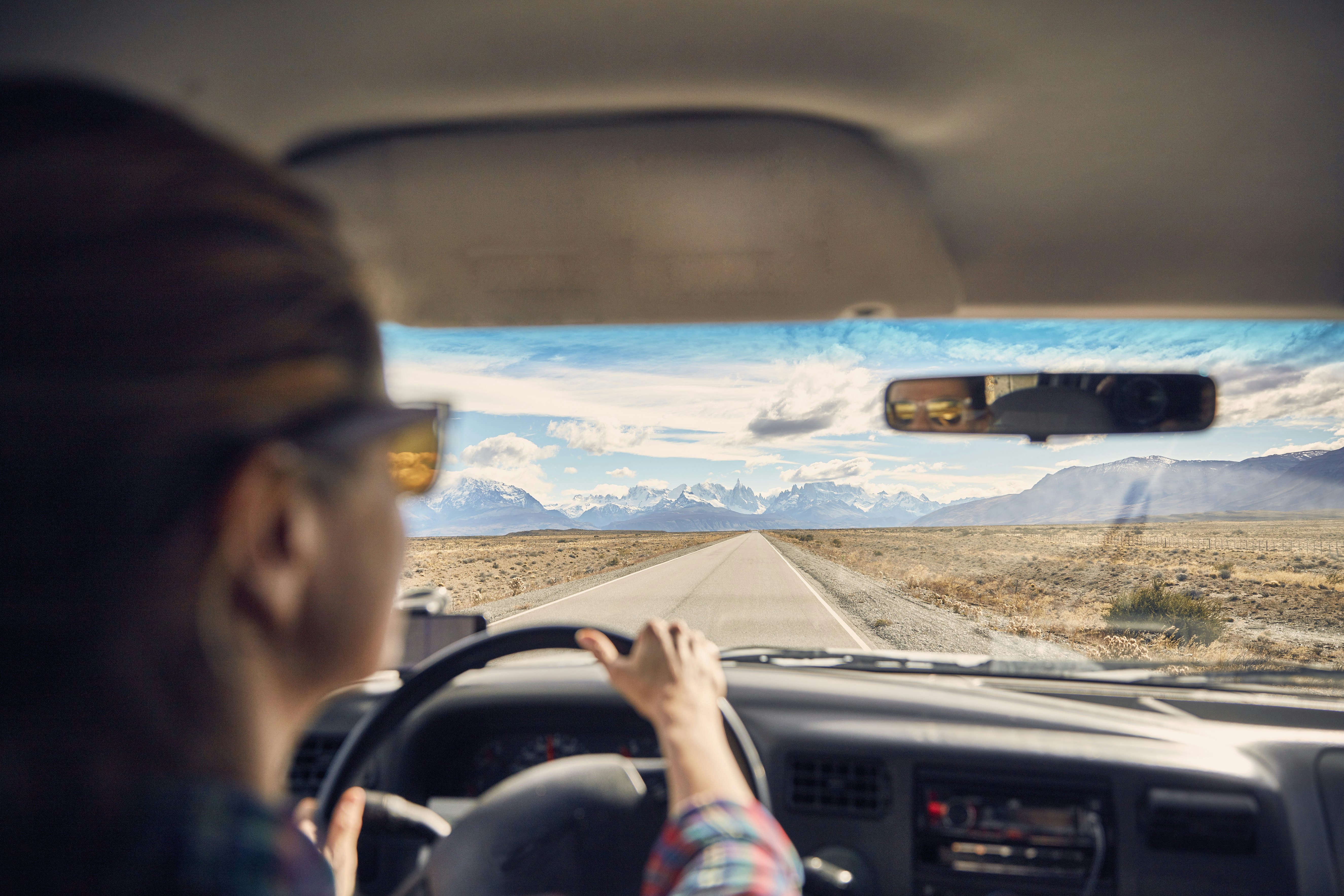 Vaizdas per automobilio langą į kelią kalnų fone