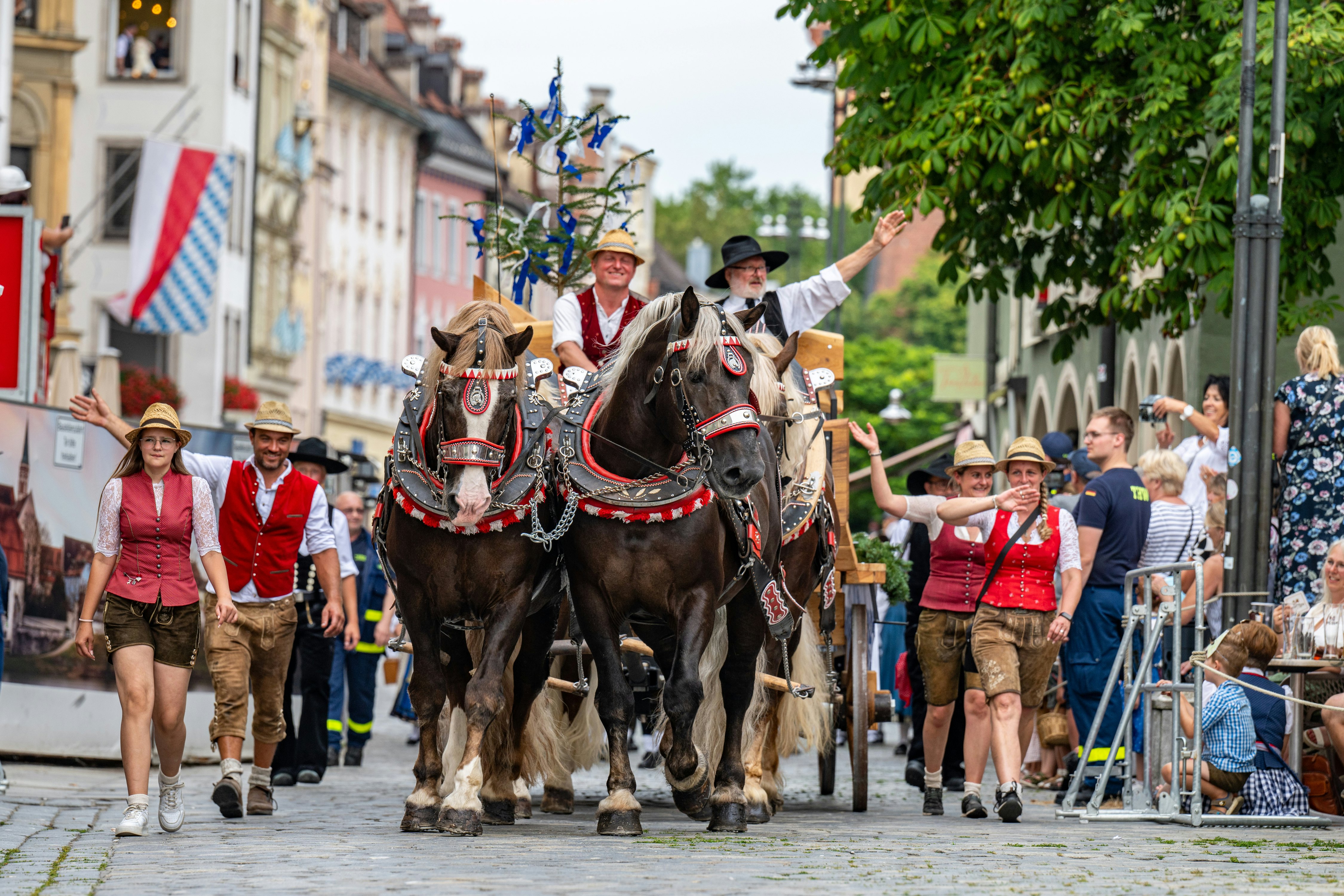 Dalyviai su tradiciniais bavarų kostiumais, vienas raitelis ant žirgo, žygiuoja per miesto centrą, pradėdami Gäubodenvolksfest šventę Straubinge.