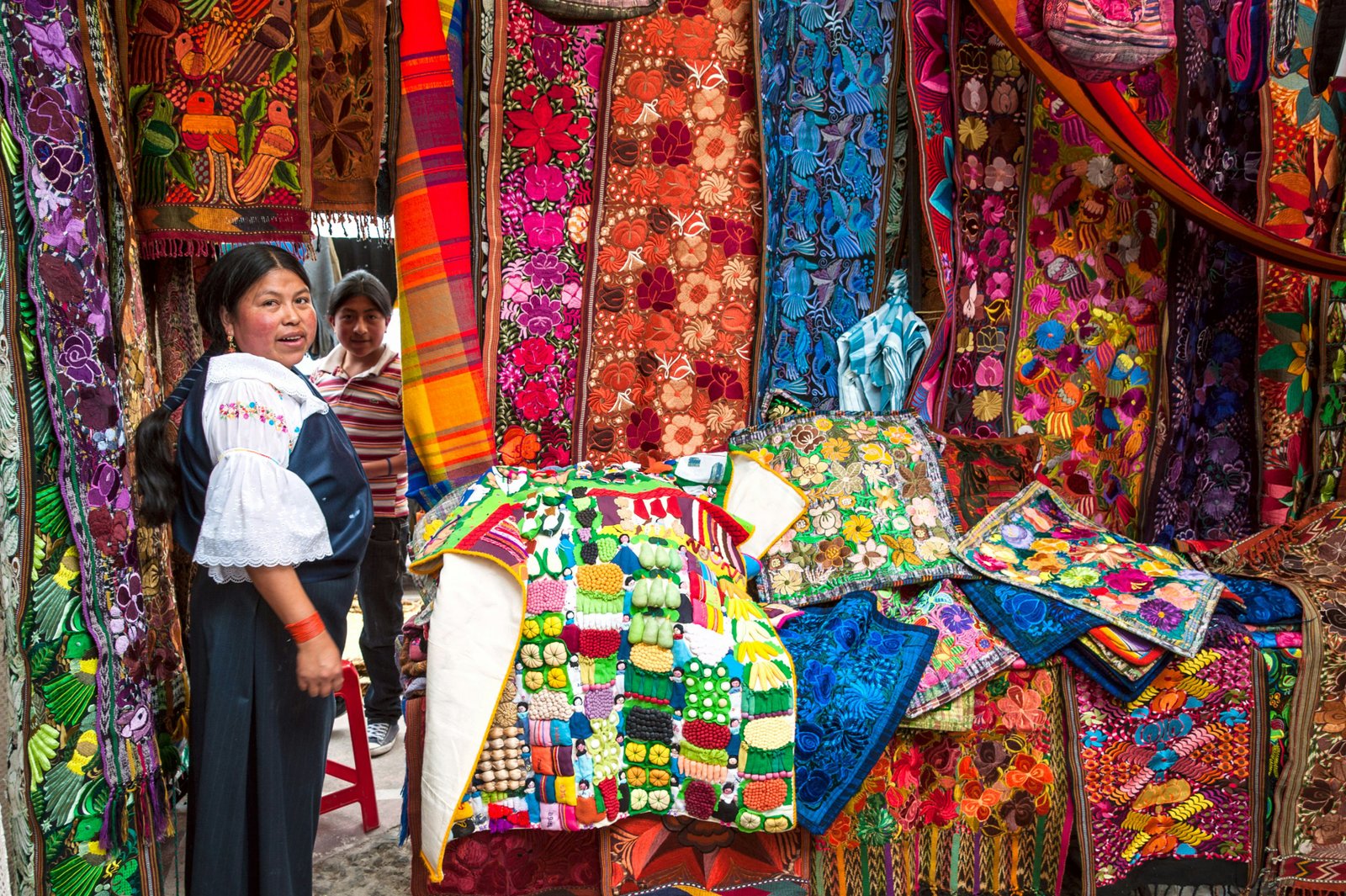 Moteris prekiauja spalvingomis prekėmis Otavalo turguje, Ekvadoras