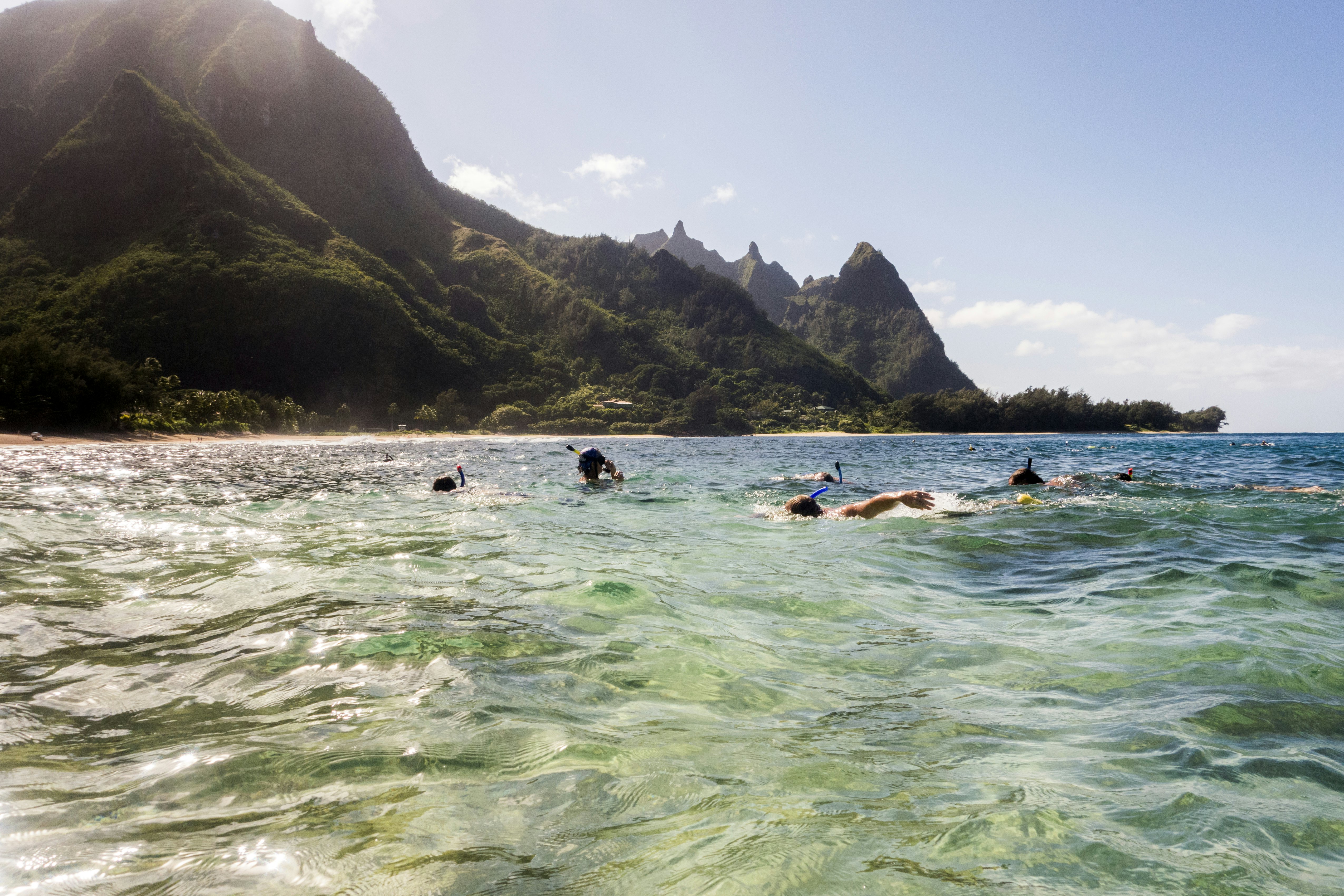 A group of people scuba diving and snorkeling off the coast of Kauaʻi on a sunny day