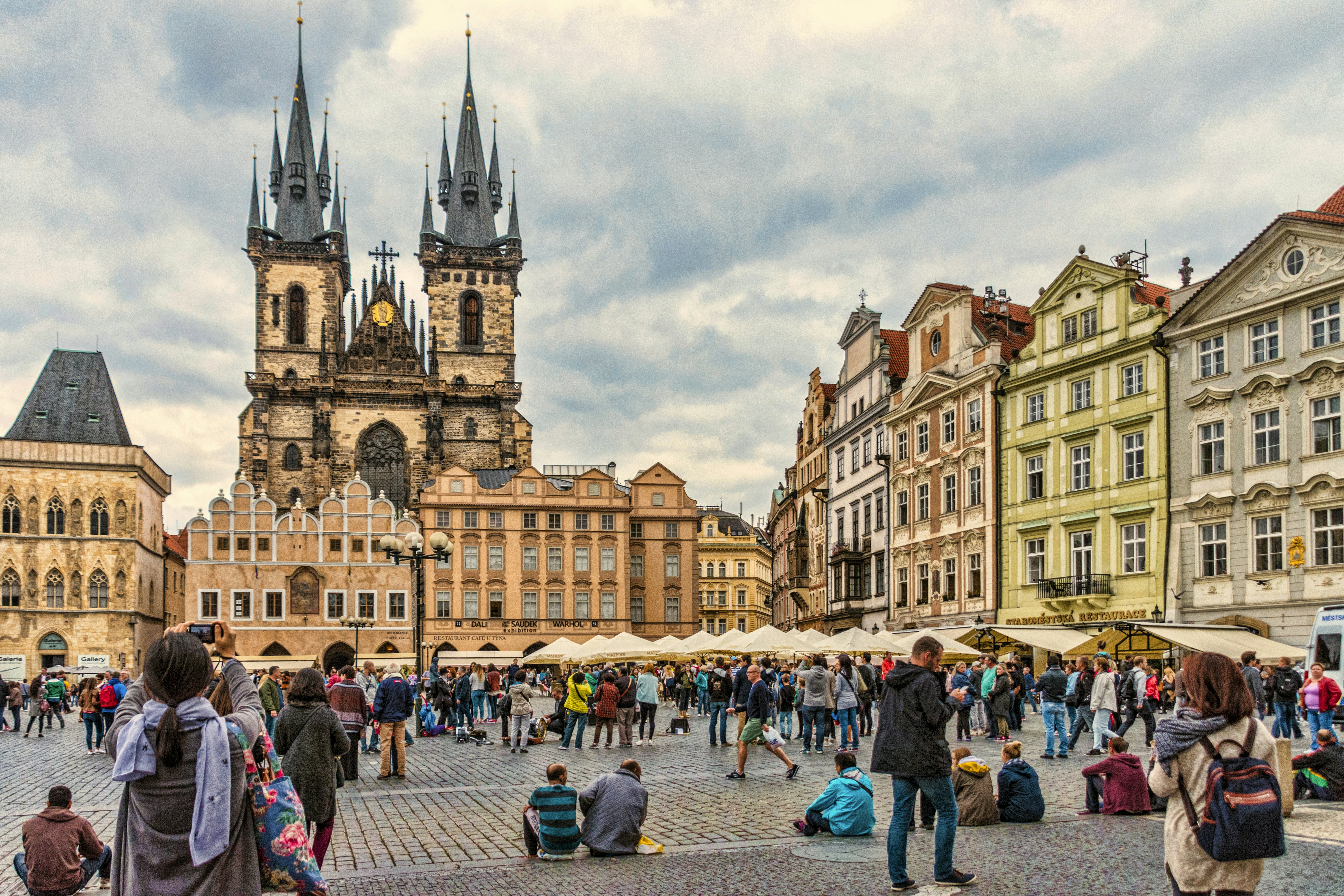 Turistai susirinkę miesto aikštėje, kurią puošia gotikiniai bažnyčios bokštai