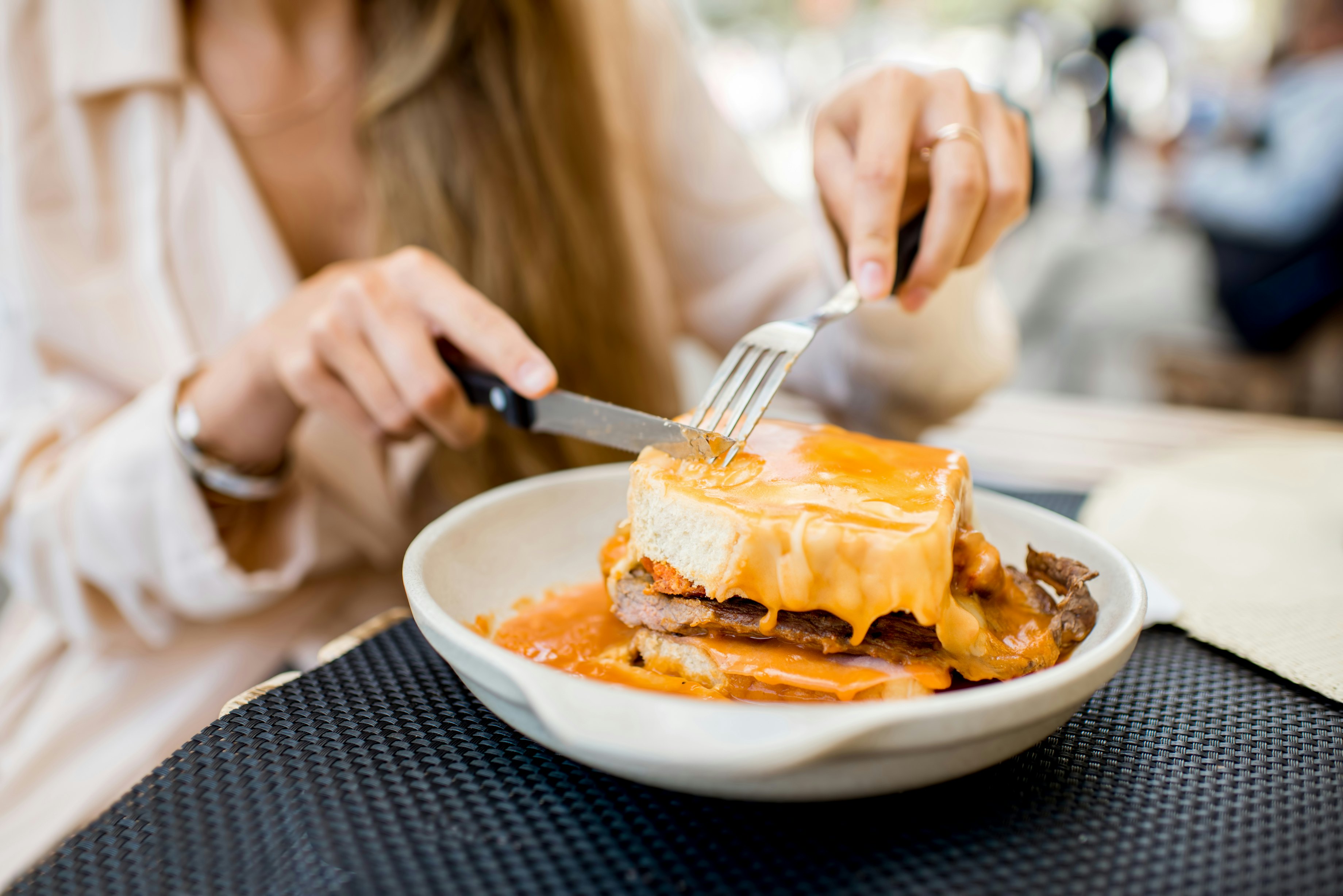 Close-up of meat sandwich covered in orange-colored sauce.
