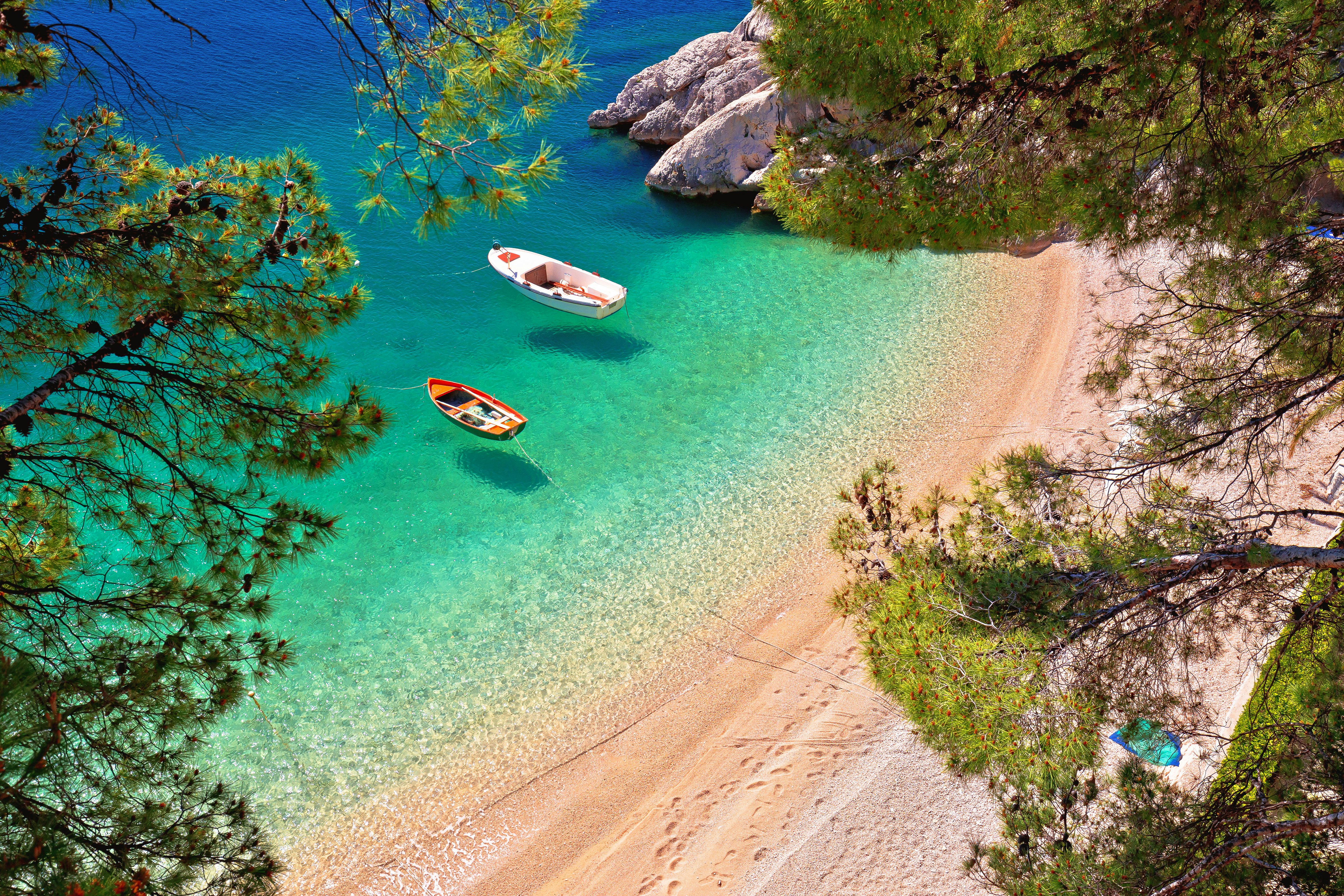 Hidden beach in Brela with boats on emerald sea aerial view, Makarska riviera of Dalmatia, Croatia