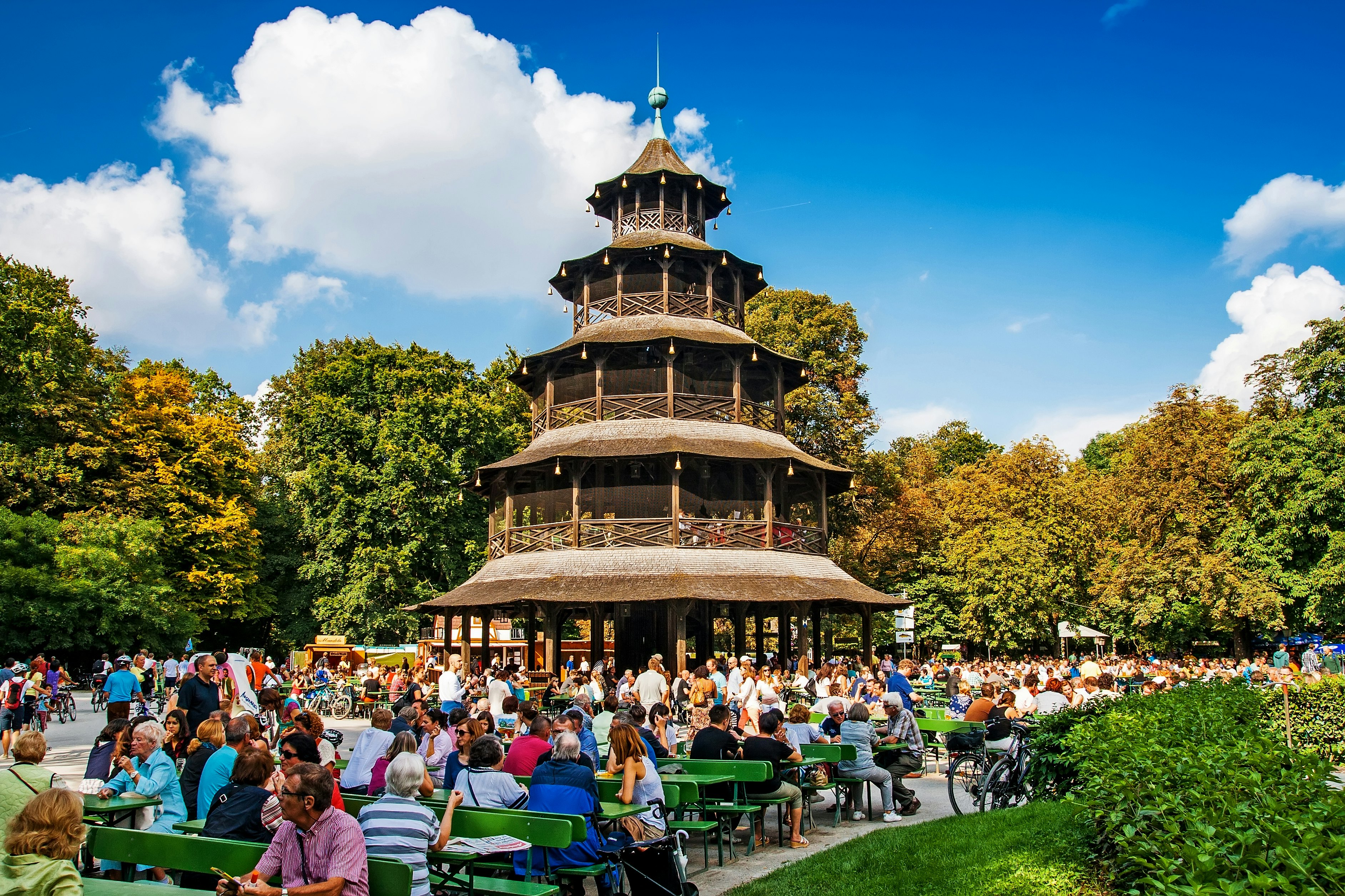 Žmonės sėdi prie stalų saulėtą dieną alaus sode šalia Kinų bokšto, Englischer Garten, Miunchene