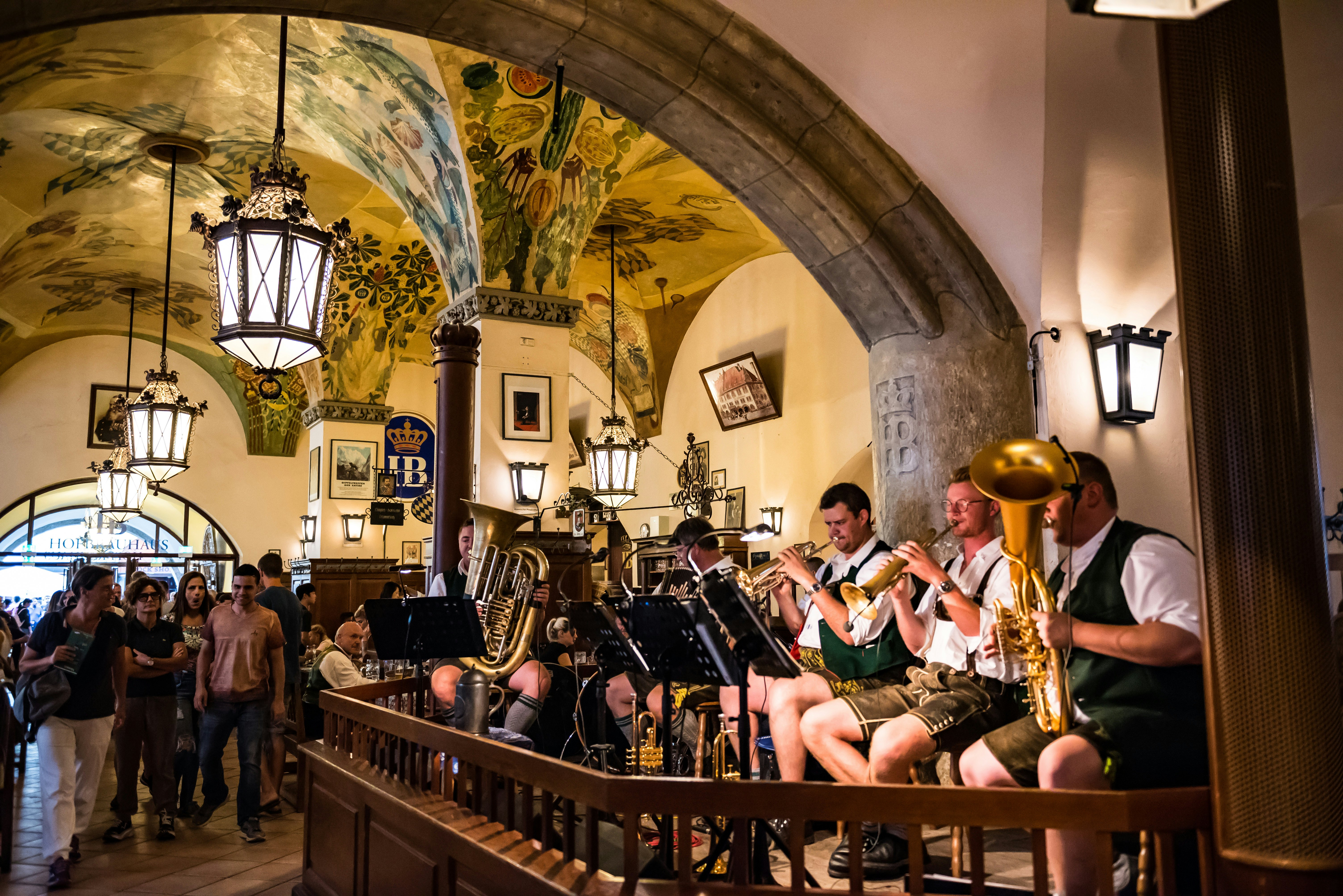 Muzikantai su tradiciniais tautiniais drabužiais groja puošnioje Hofbräuhaus salėje, Miunchene