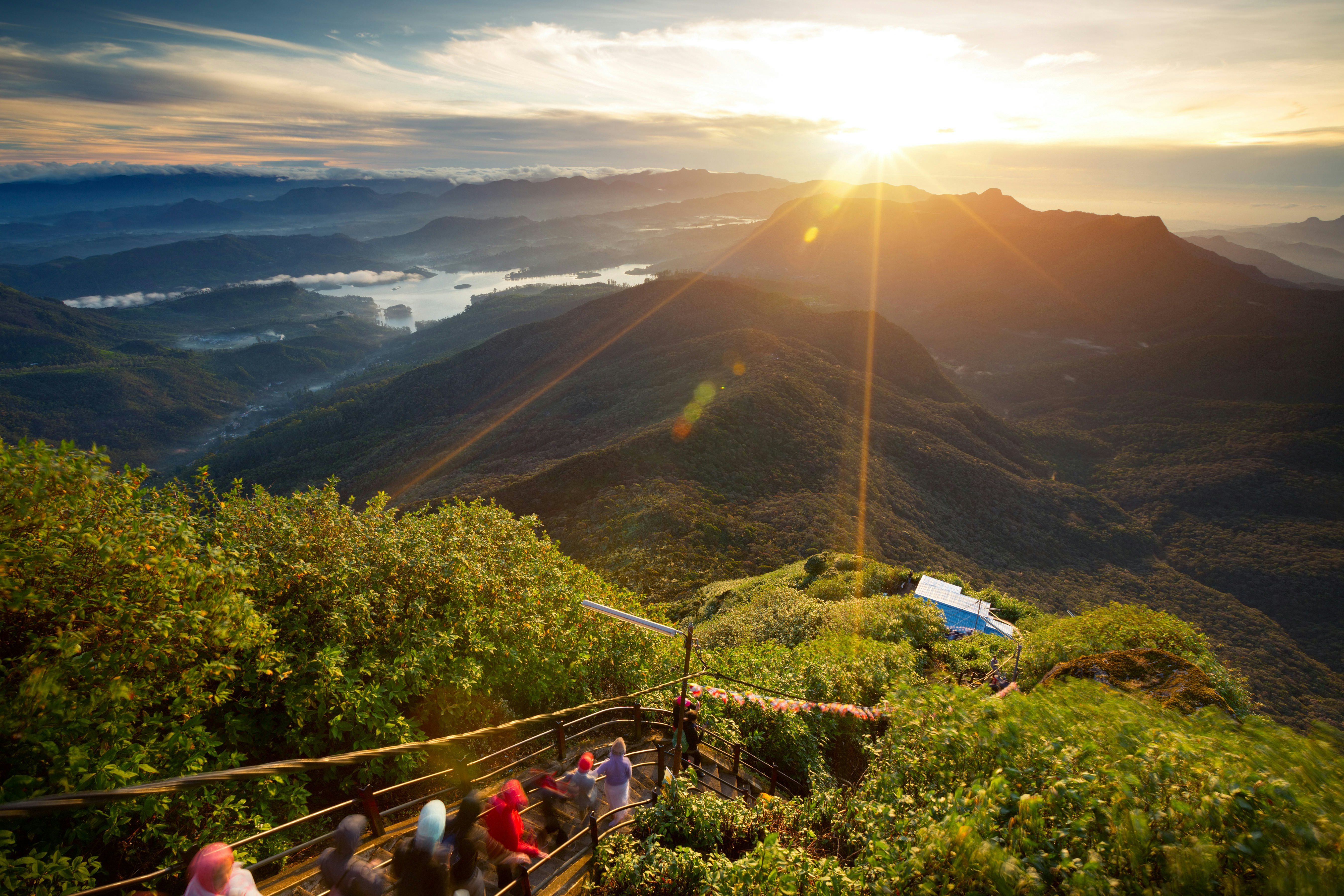 Piligrimai leidžiasi laiptais su įspūdingu Saulės pakilimu nuo Adam's Peak kalno viršūnės, Šri Lanka