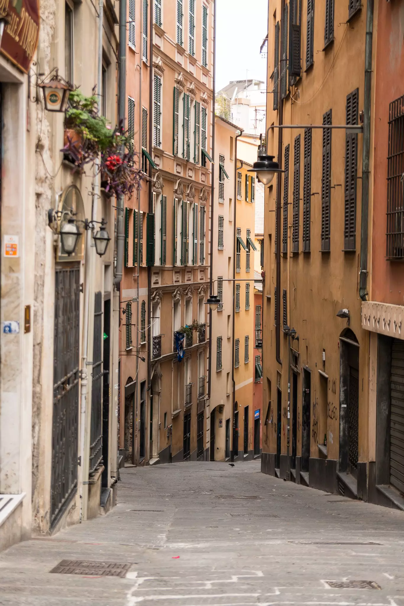 A narrow street with yellow and terracotta buildings, tightly packed together.